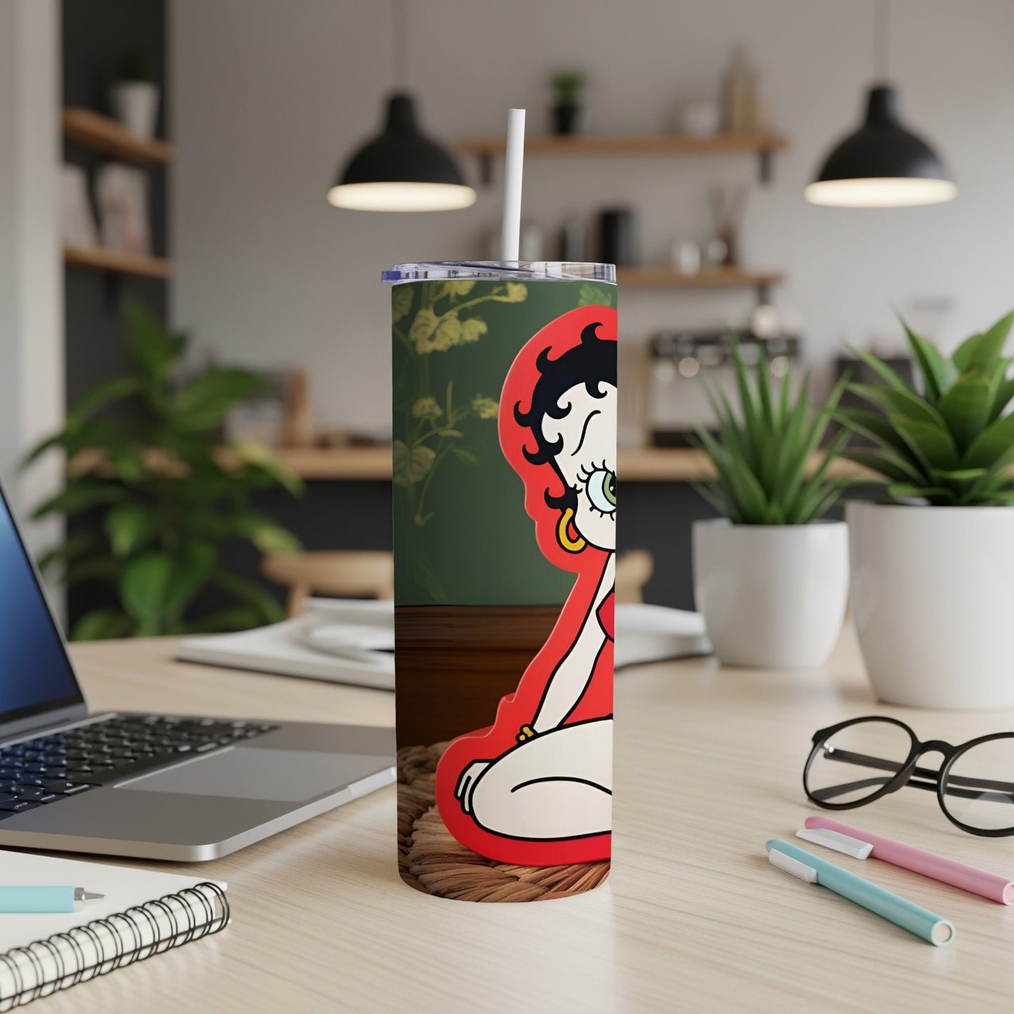 Betty Boop illustration on a white tumbler with a straw, on a desk.