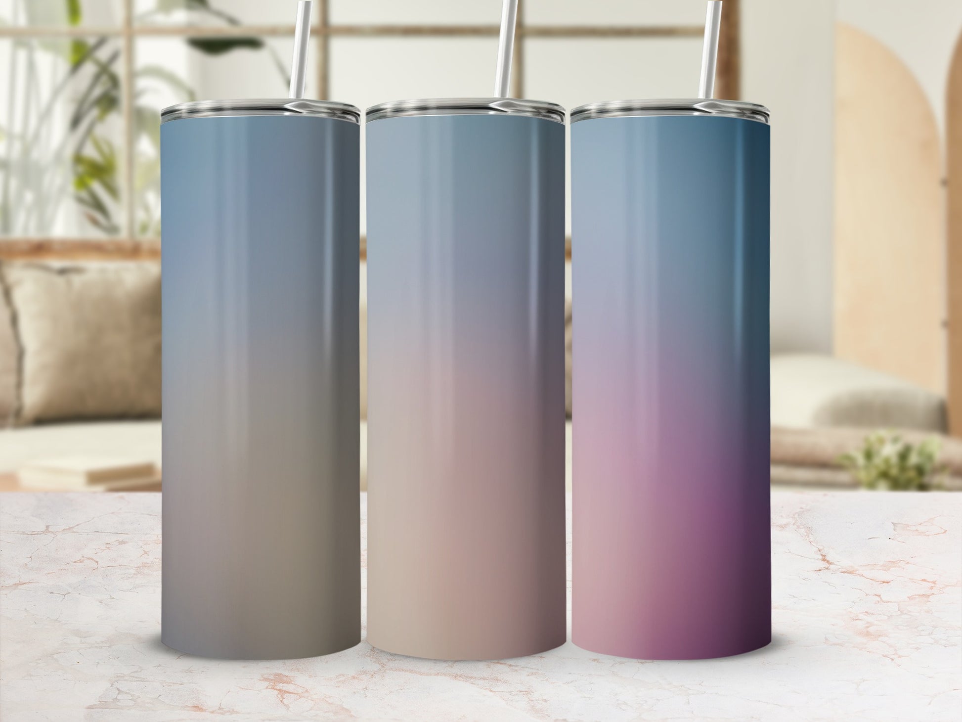 Three gradient tumblers with straws on a marble surface.