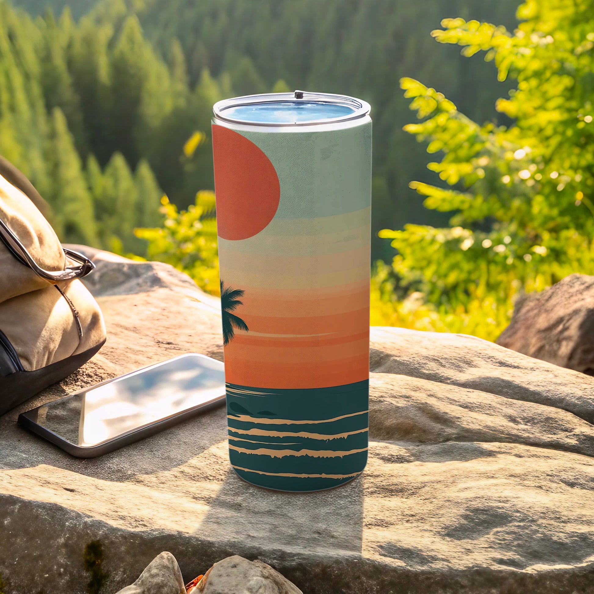 Sunset beach scene on a stainless steel tumbler next to a phone.