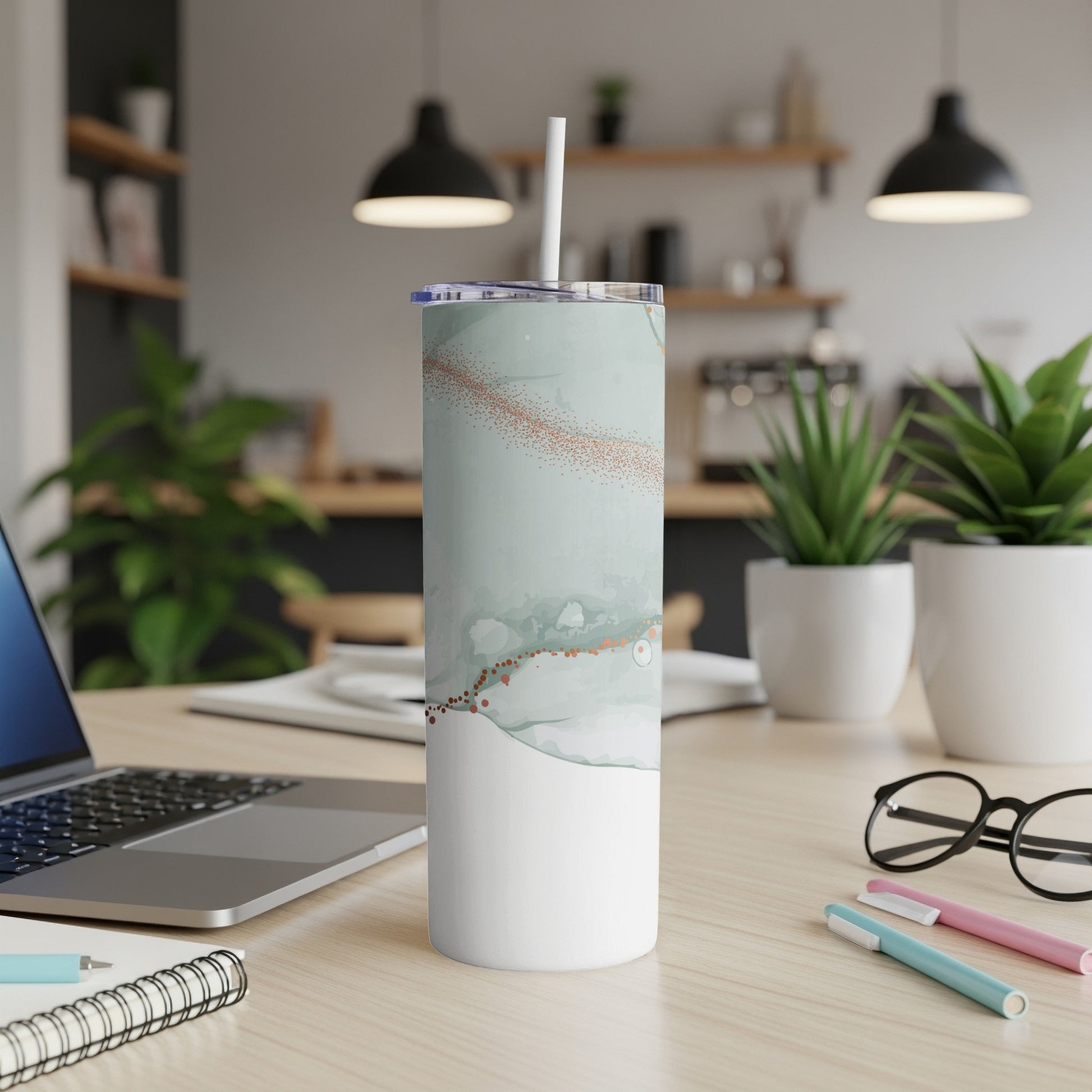 White tumbler with marble and rose gold design, on a desk.