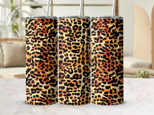 Three leopard print tumblers with straws on a marbled countertop.