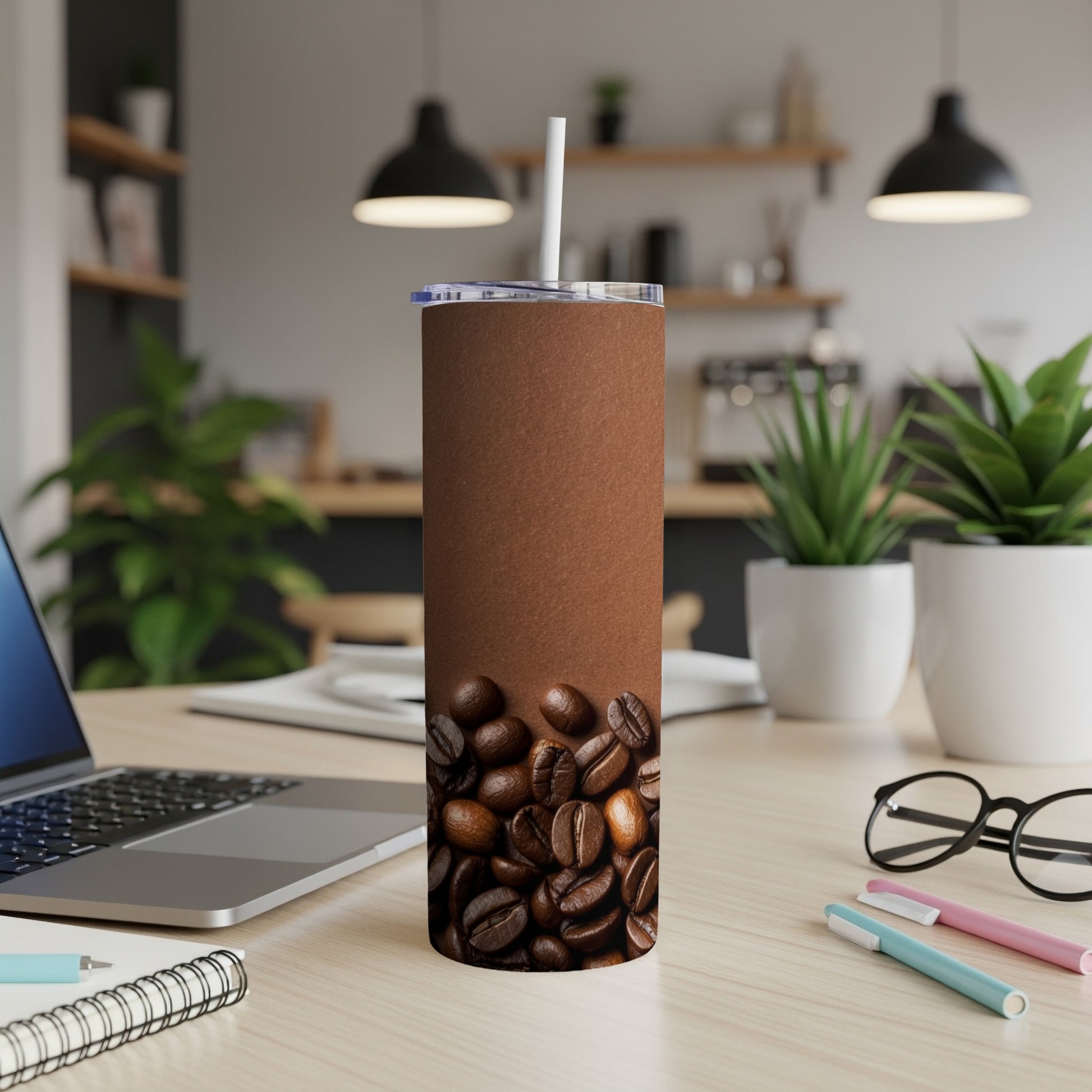 Brown tumbler with coffee beans and white straw on a desk.