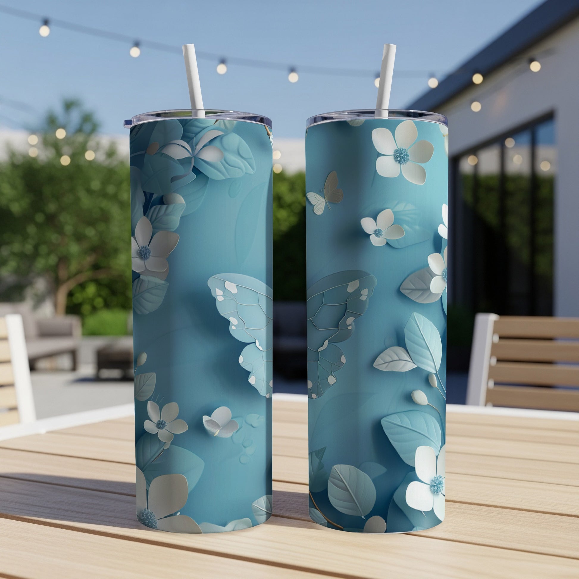 Two blue tumblers with butterfly and floral patterns on a wooden table.