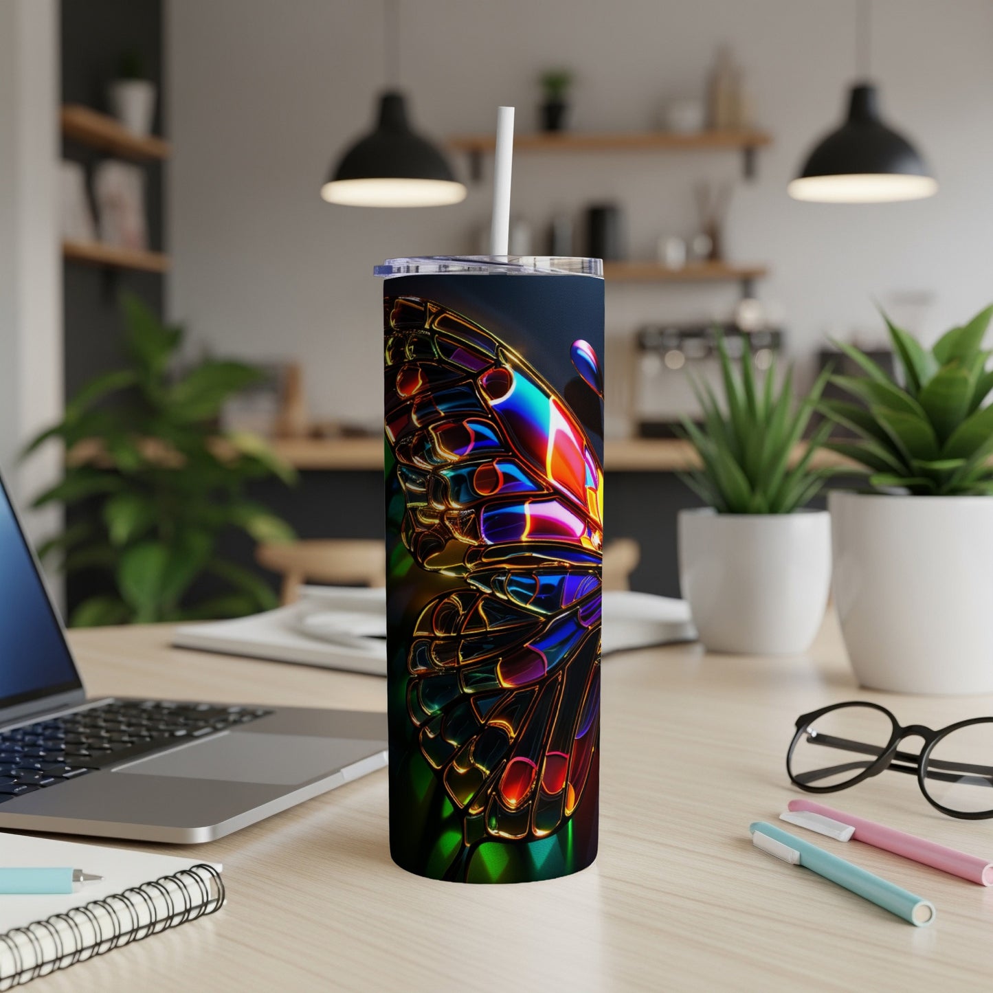 Tumbler with iridescent butterfly design on desk next to laptop.