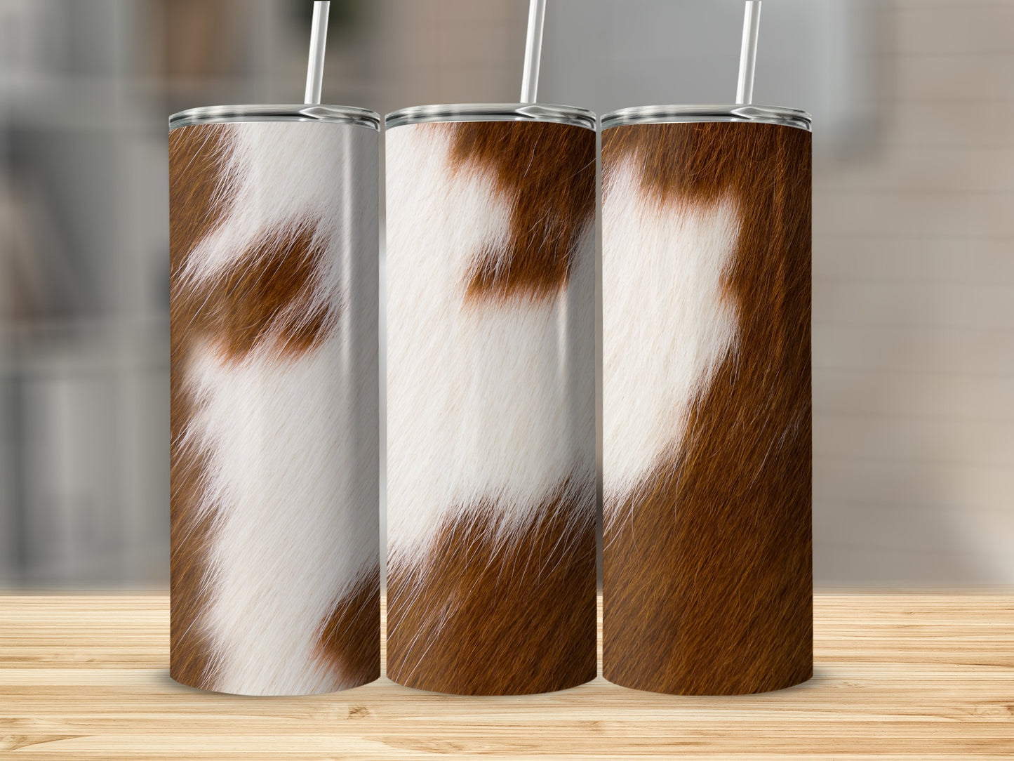 Three tumblers with brown and white cowhide print and straws.