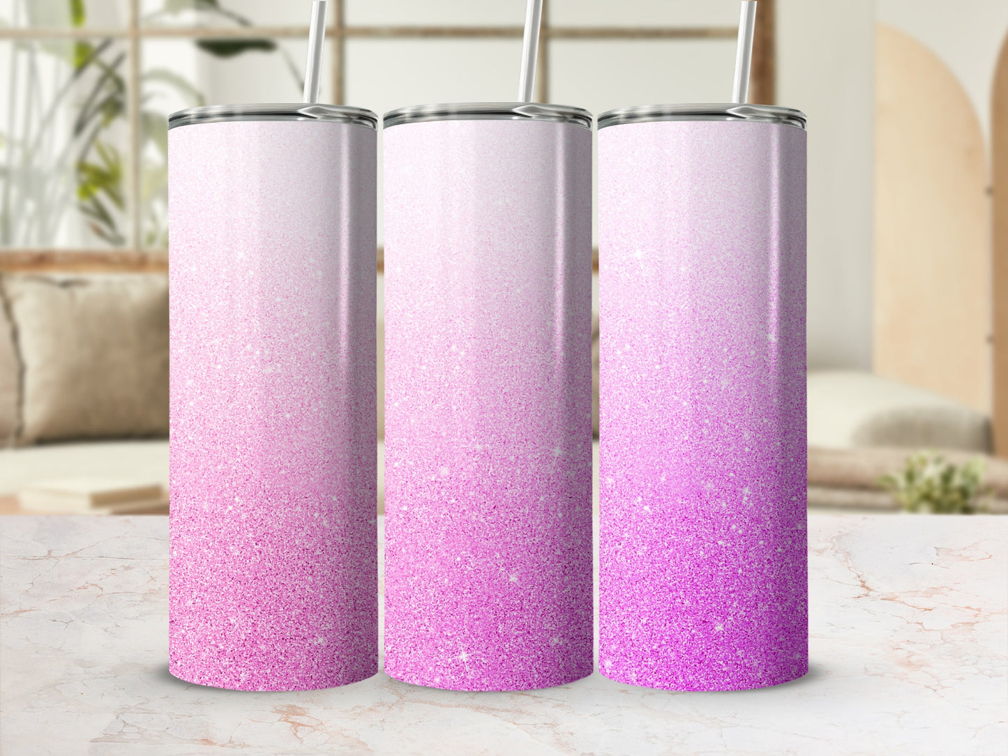 Three pink glitter gradient tumblers with straws on a marble surface.