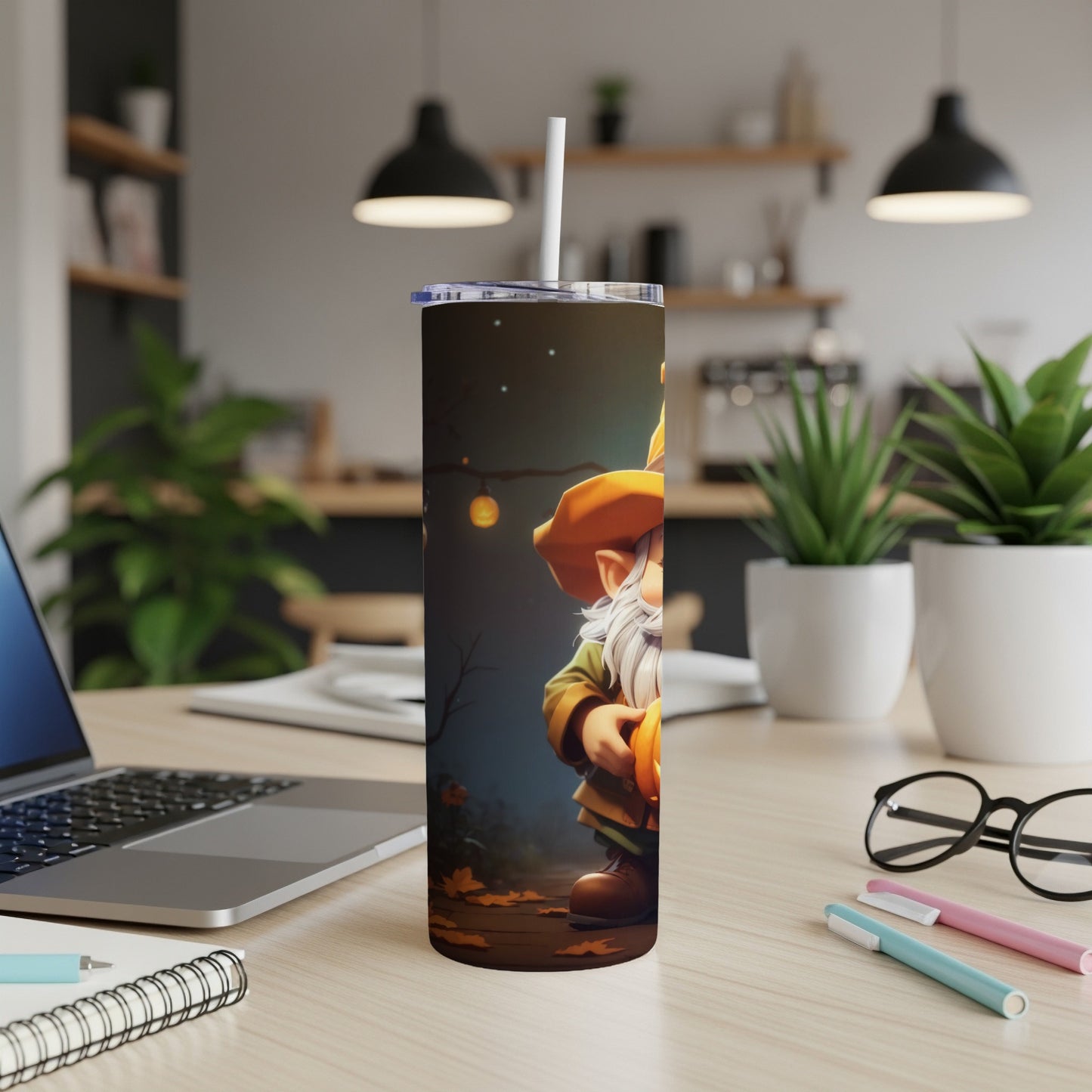 Tumbler with gnome holding pumpkin, on desk with laptop and plants