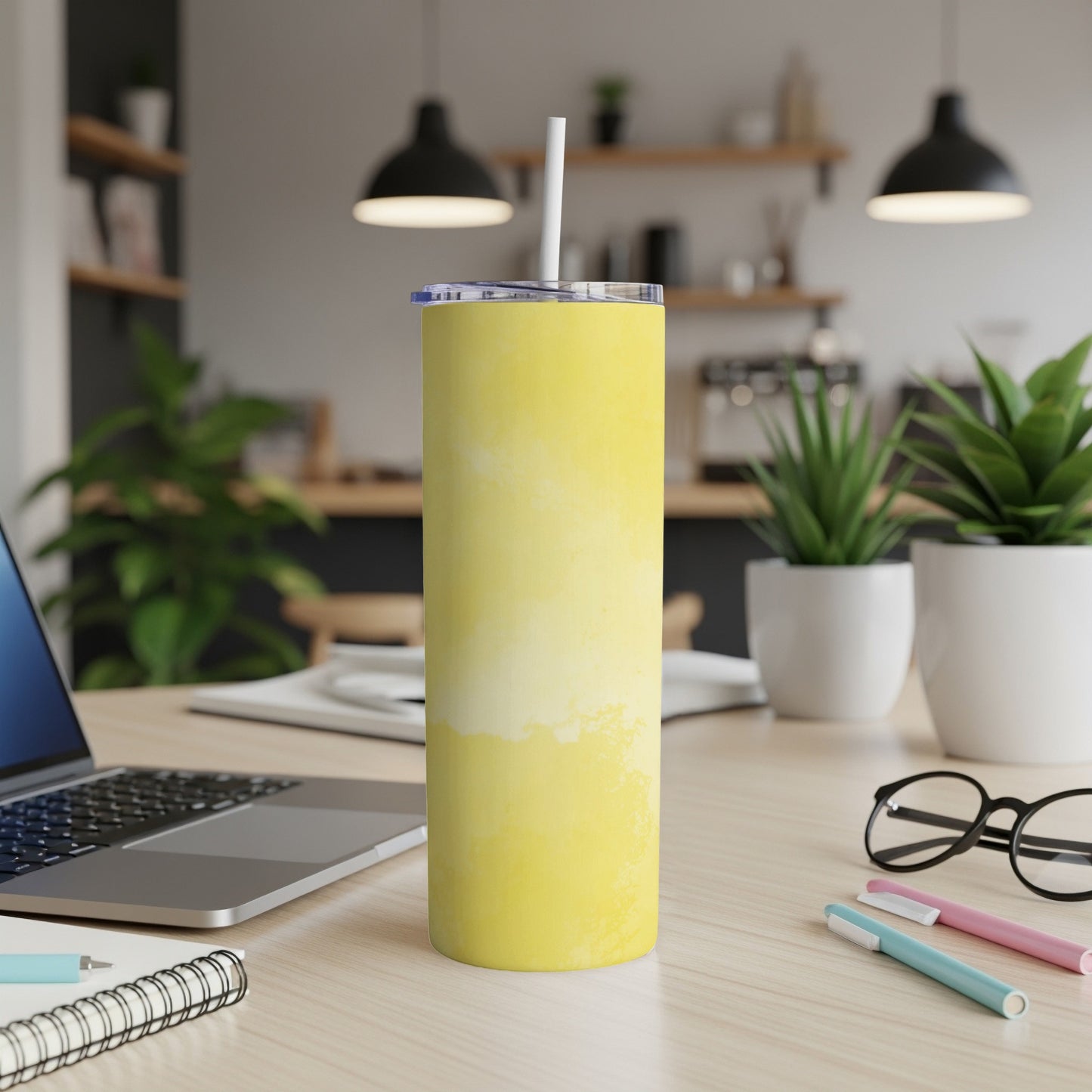 Yellow marbled tumbler with straw on a desk next to a laptop.