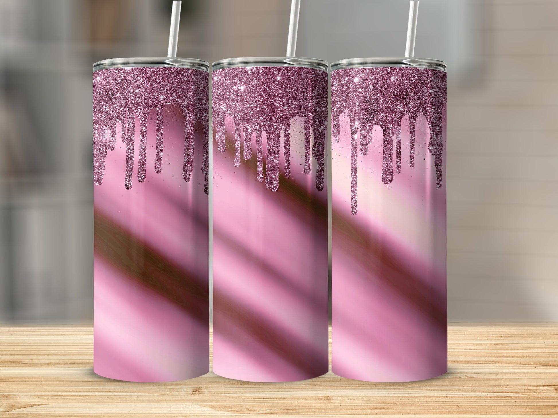 Three pink glitter drip tumblers with straws on a wooden surface.