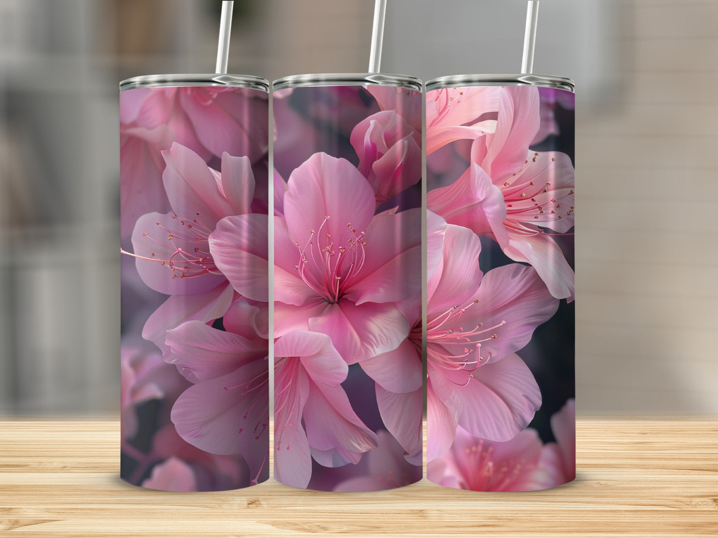 Pink azalea flowers adorn three tumblers with straws on a wooden surface.