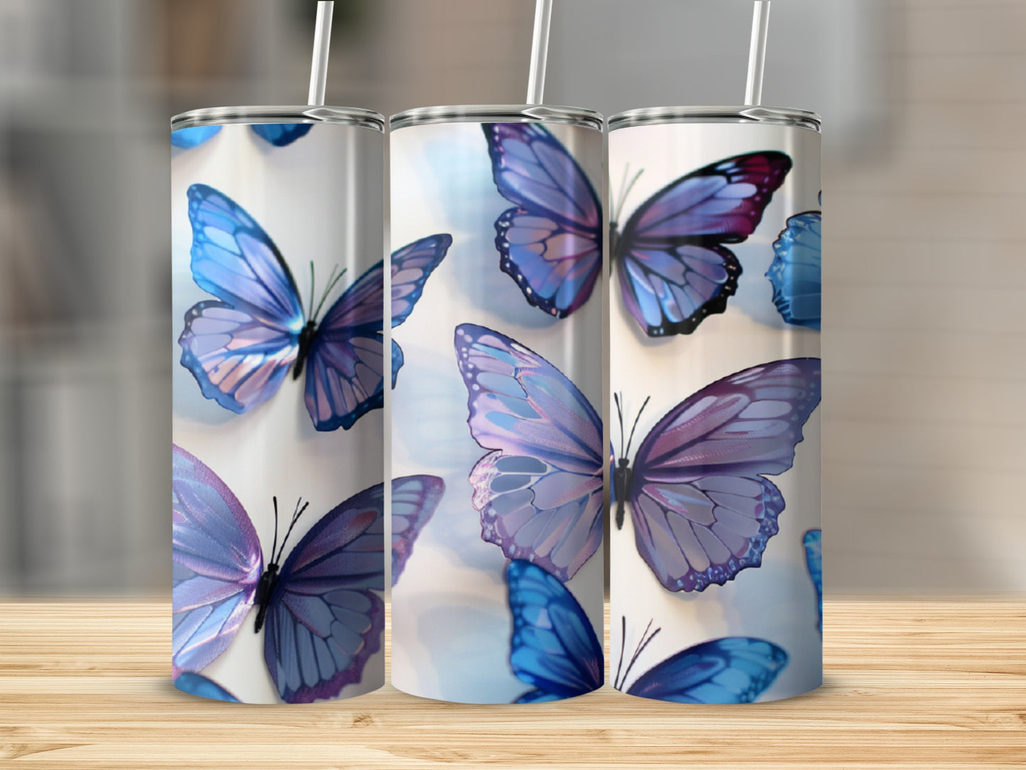 Three tumblers with iridescent blue butterflies, on a wooden surface.