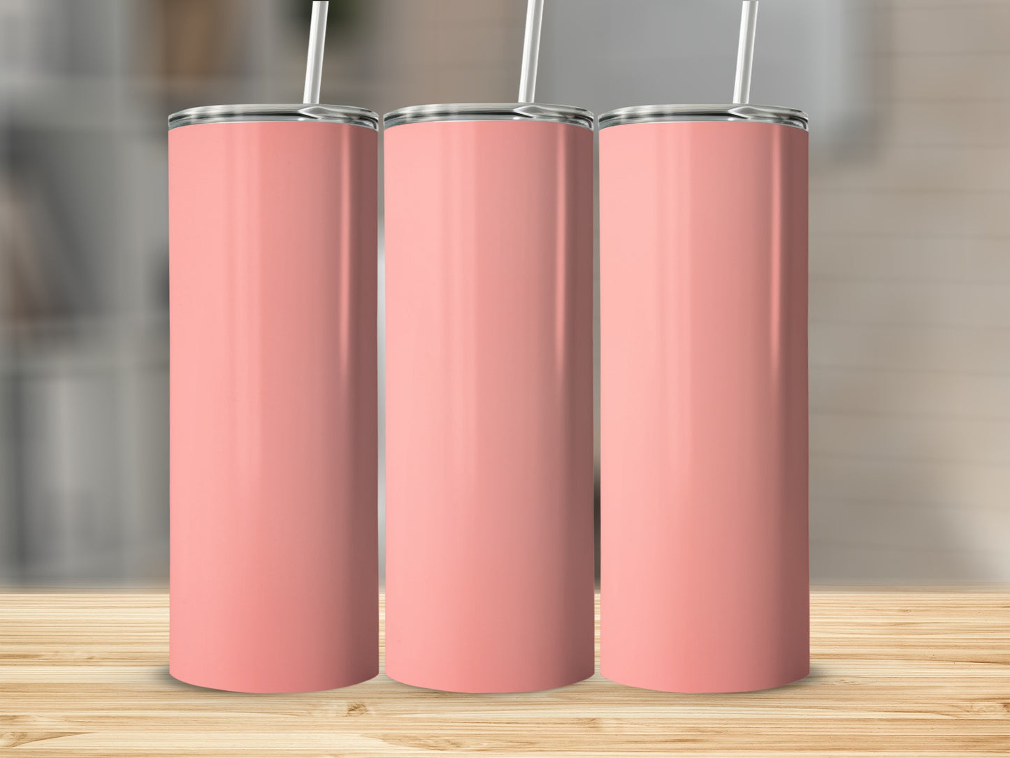 Three tall, coral-colored tumblers with white straws stand on a wooden surface.