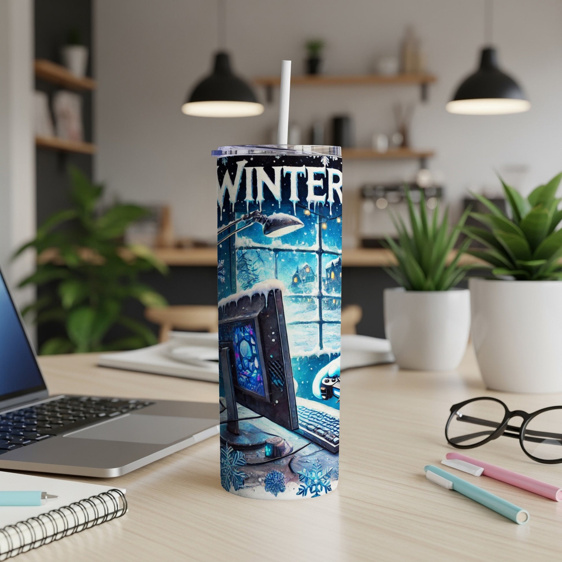 Winter-themed tumbler with computer and snowflakes, on a desk.