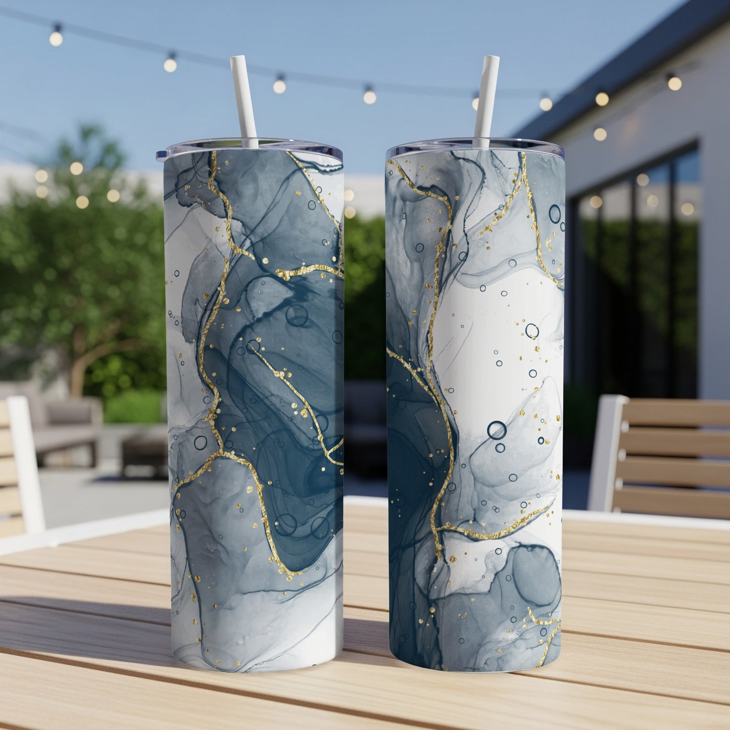 Two tumblers with a marbled blue and gold abstract design on a wooden table.