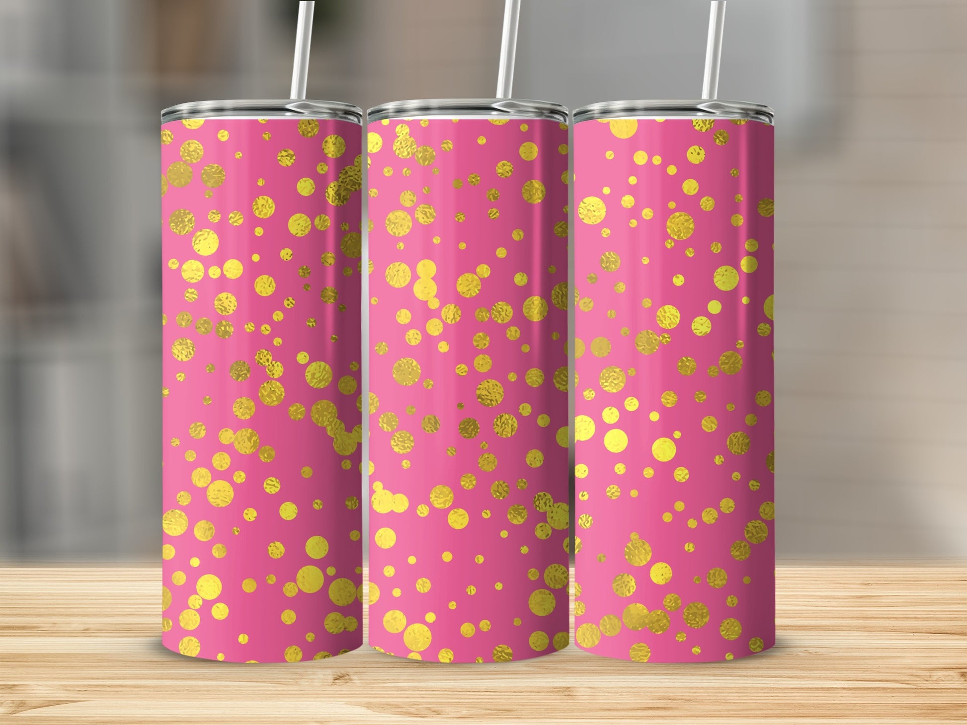 Three pink tumblers with gold polka dot pattern on a wooden surface.