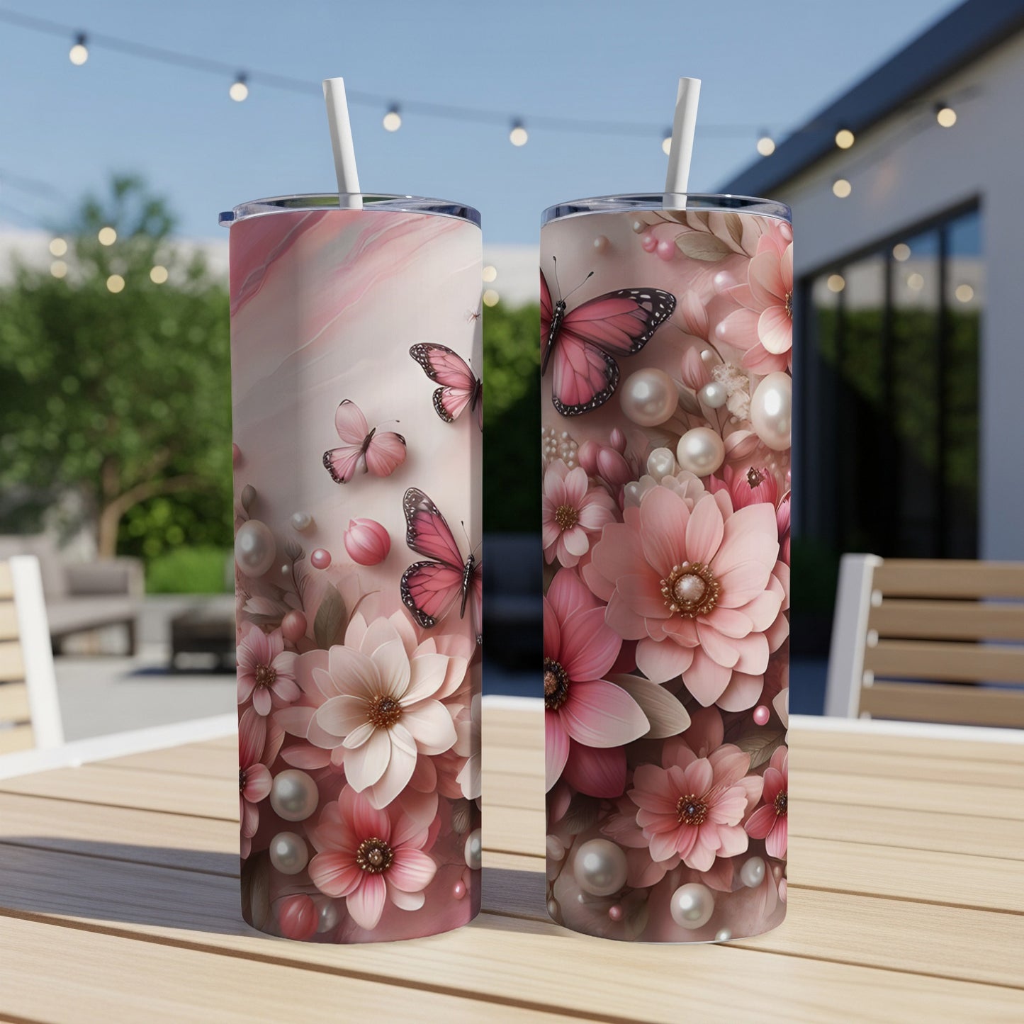 Two floral patterned tumblers with pink butterflies and pearls on a table.