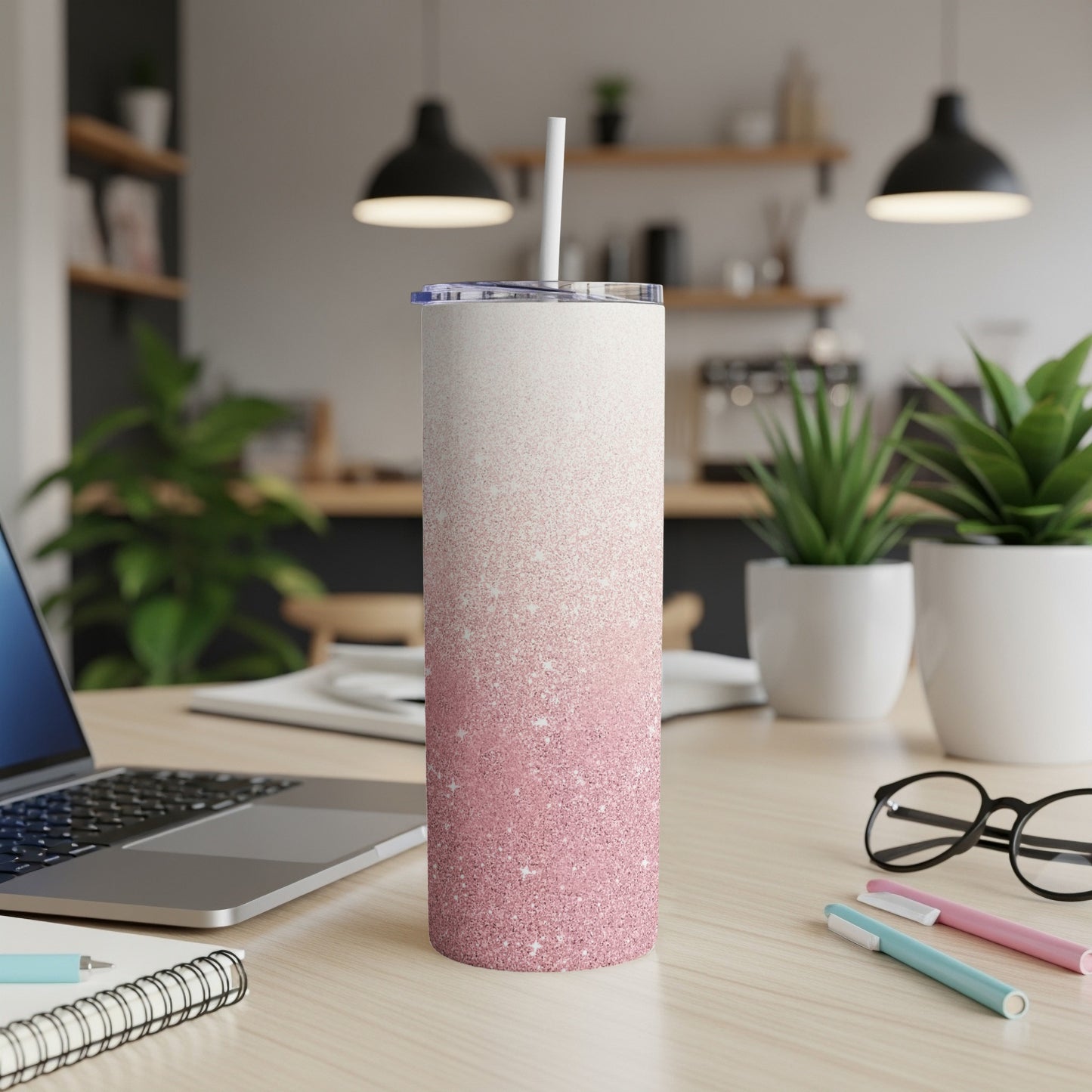 Glitter gradient pink and white tumbler with straw on desk.