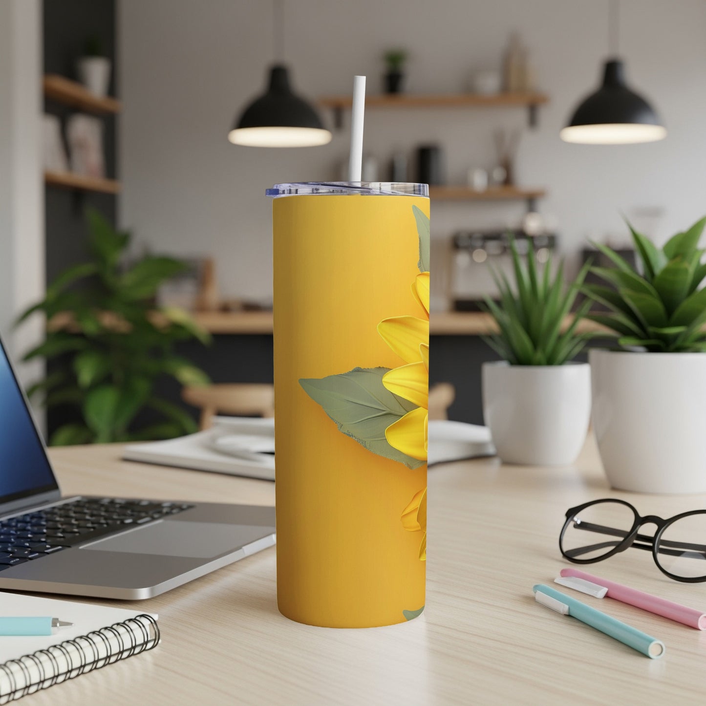 Yellow tumbler with a sunflower illustration on a desk.