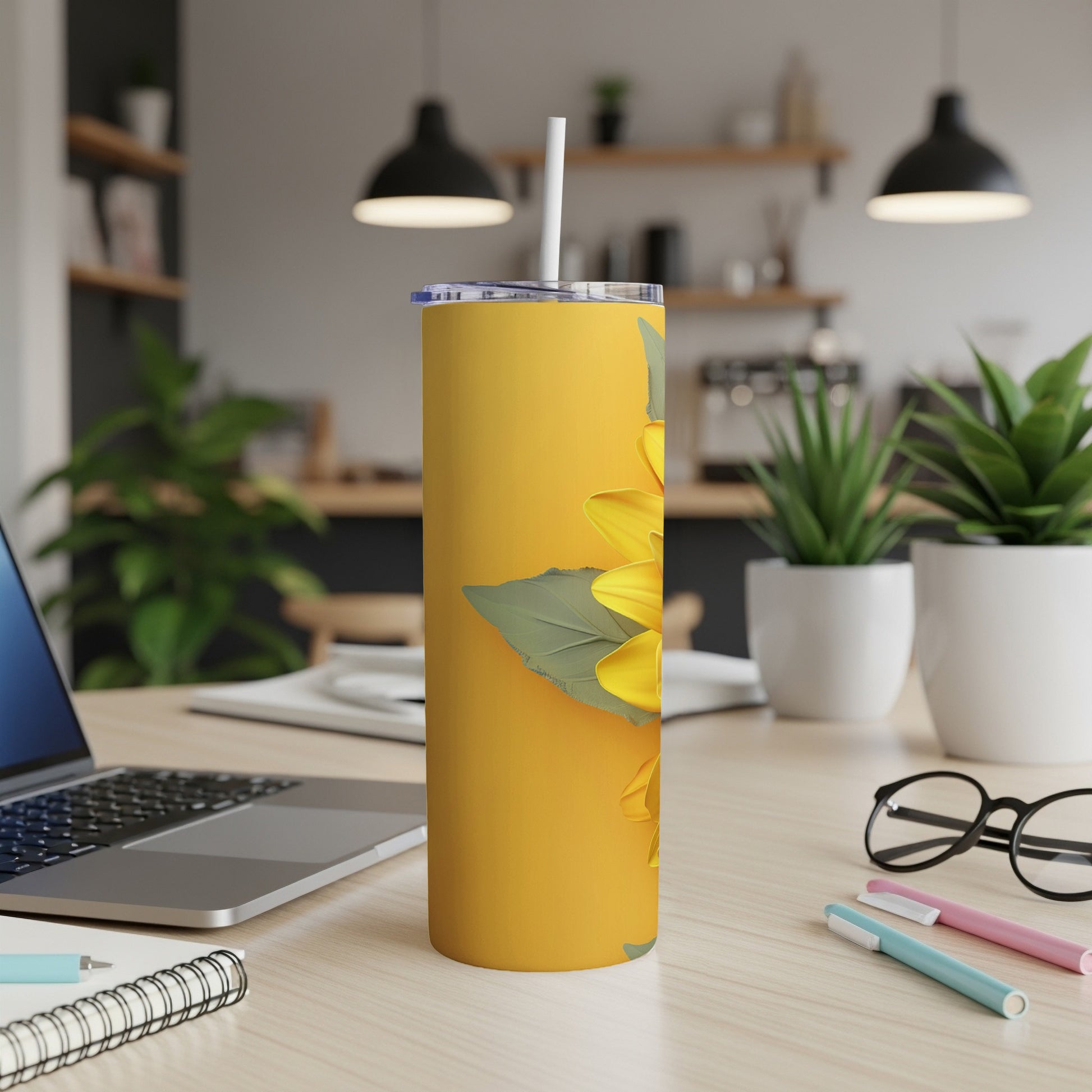 Yellow tumbler with a sunflower illustration on a desk.