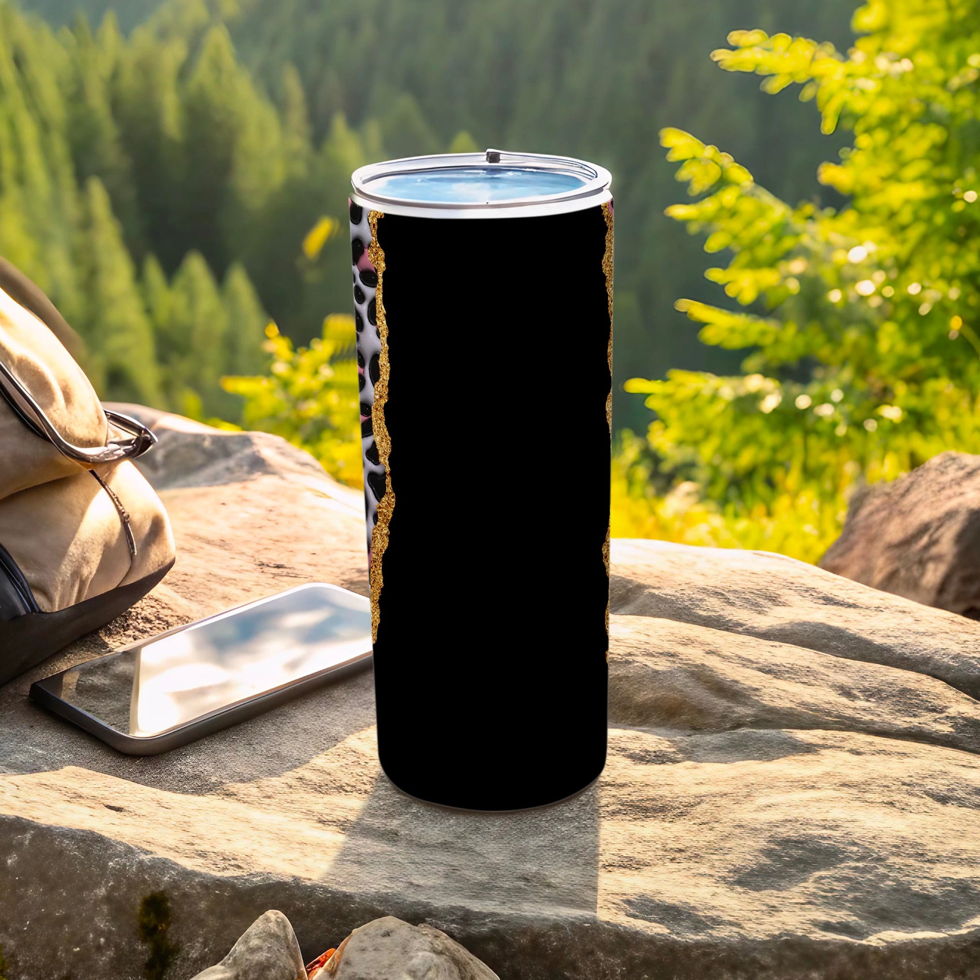 Black tumbler with leopard print and gold glitter detail on a rock.