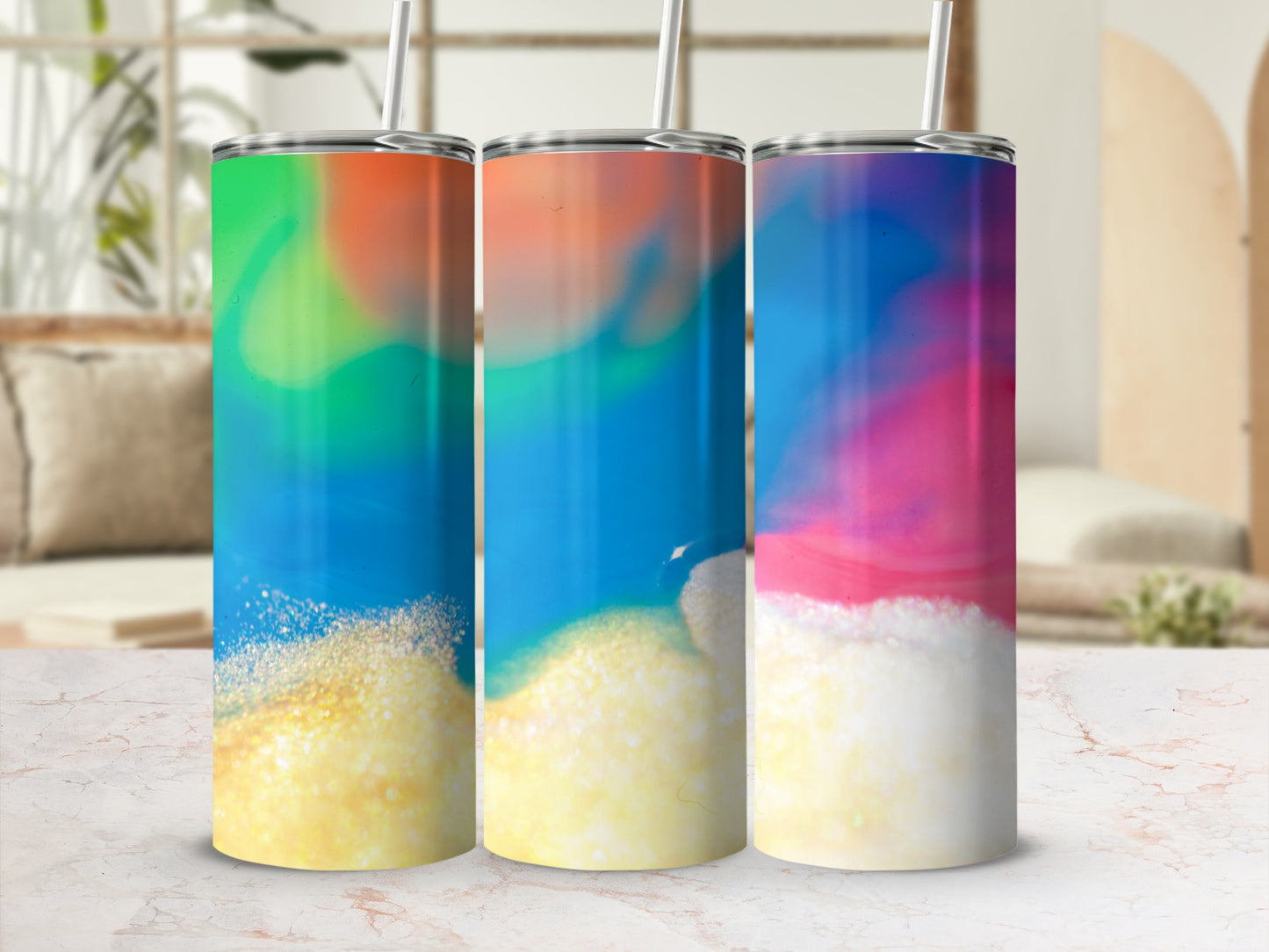 Three tumblers with colorful abstract designs and straw in a bright setting.