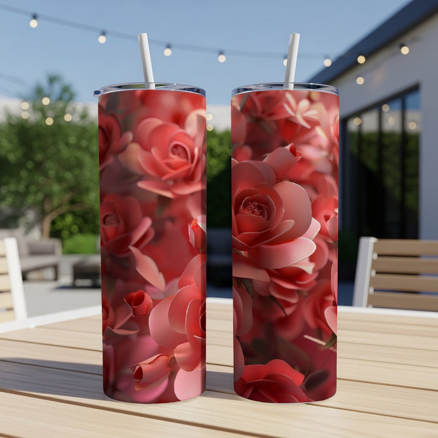 Two pink rose pattern tumblers on a table with a blurred outdoor background.