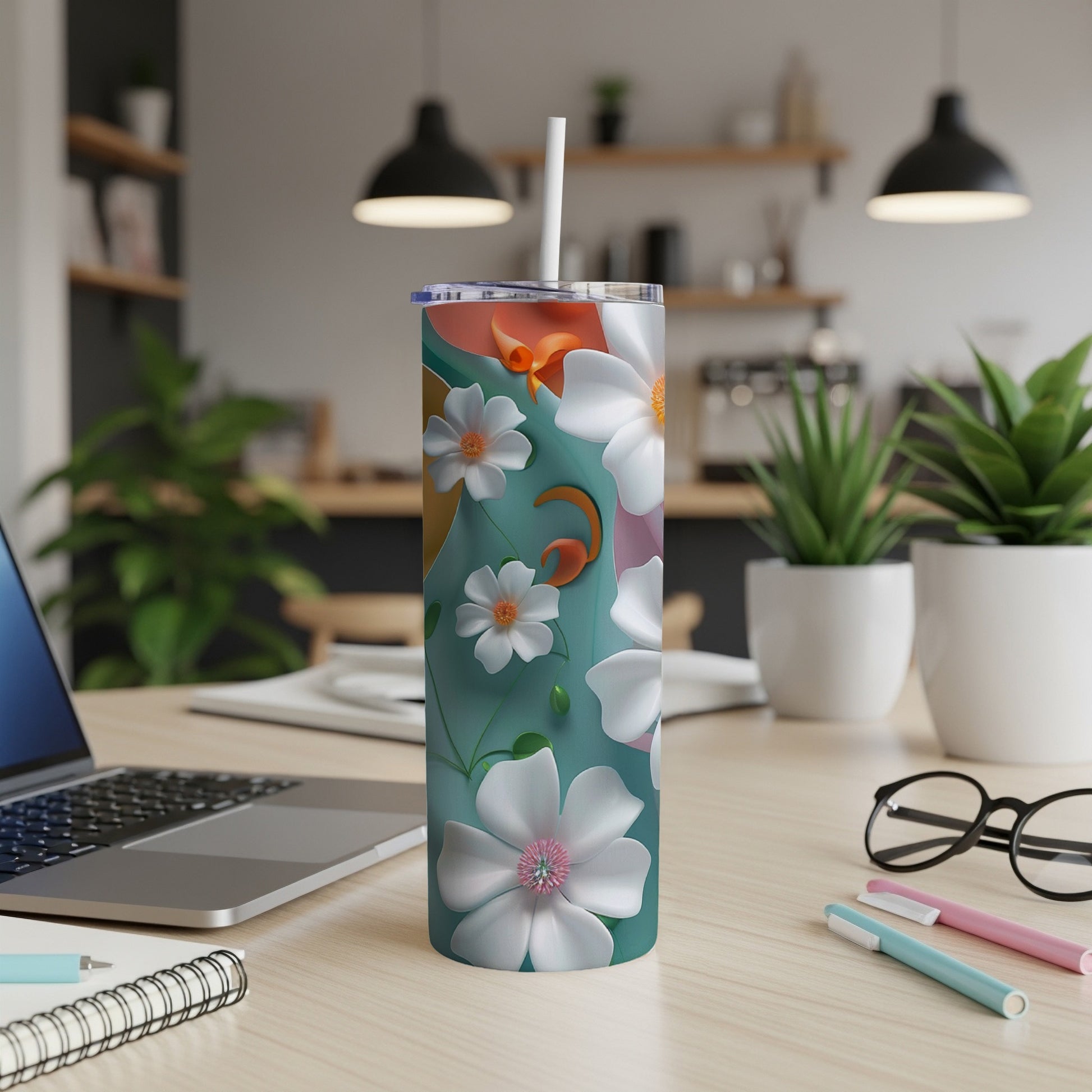 Teal tumbler with abstract floral pattern and white straw on desk.