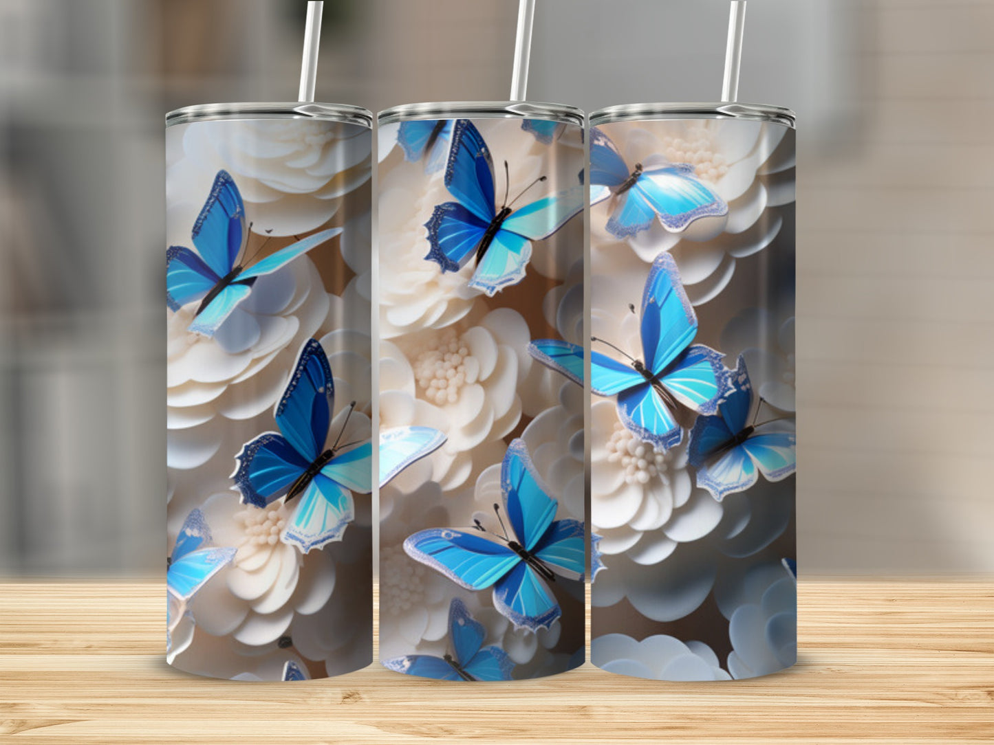 Three tumblers with blue butterflies and white flowers on a wooden surface.