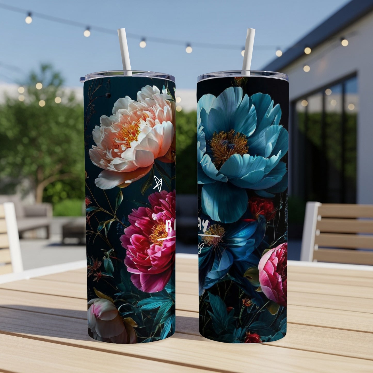 Two tumblers with floral designs, one pink and one blue, sit on a table.