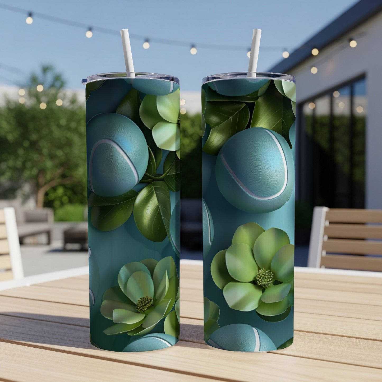 Two teal tumblers with tennis balls and green leaves pattern on a table.