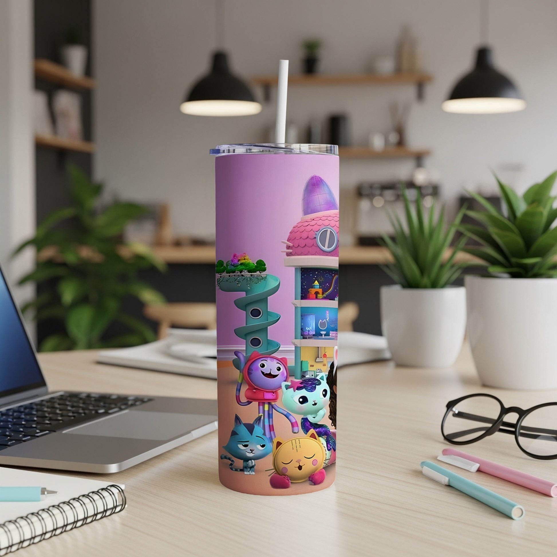 Gabby's Dollhouse characters on a pink tumbler with a straw, on a desk.