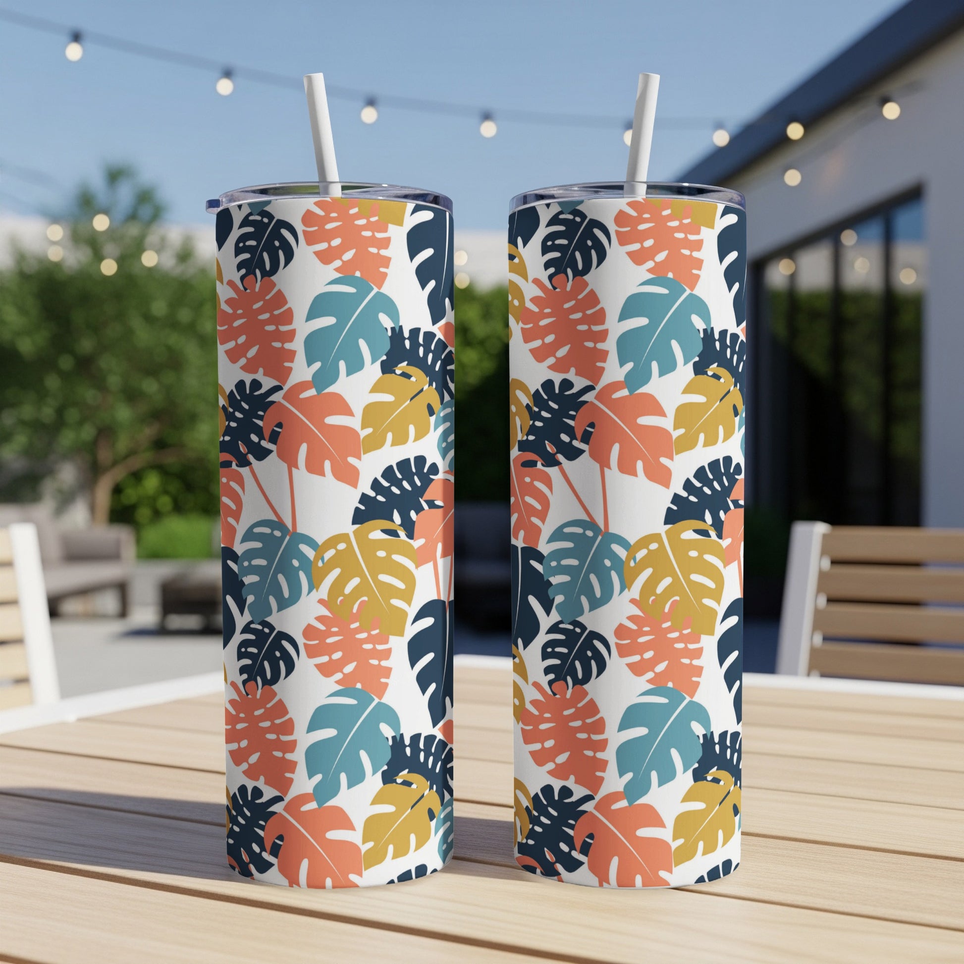 Two tall tumblers with a monstera leaf pattern in teal, coral, and yellow.
