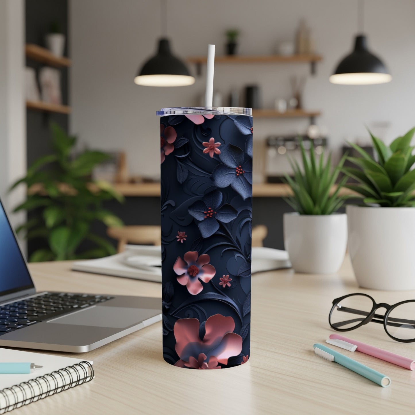 Dark blue floral tumbler with a straw on a desk.