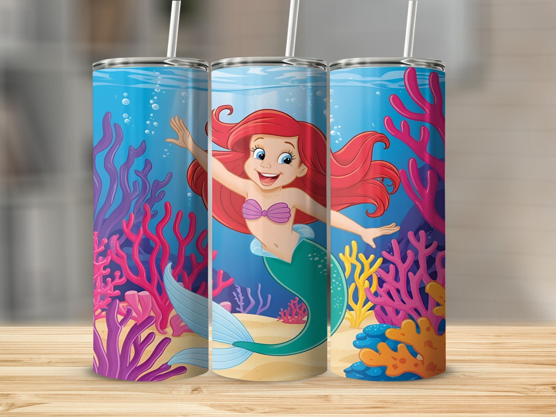 Ariel the mermaid smiles and waves on a blue tumbler with coral and sea life.