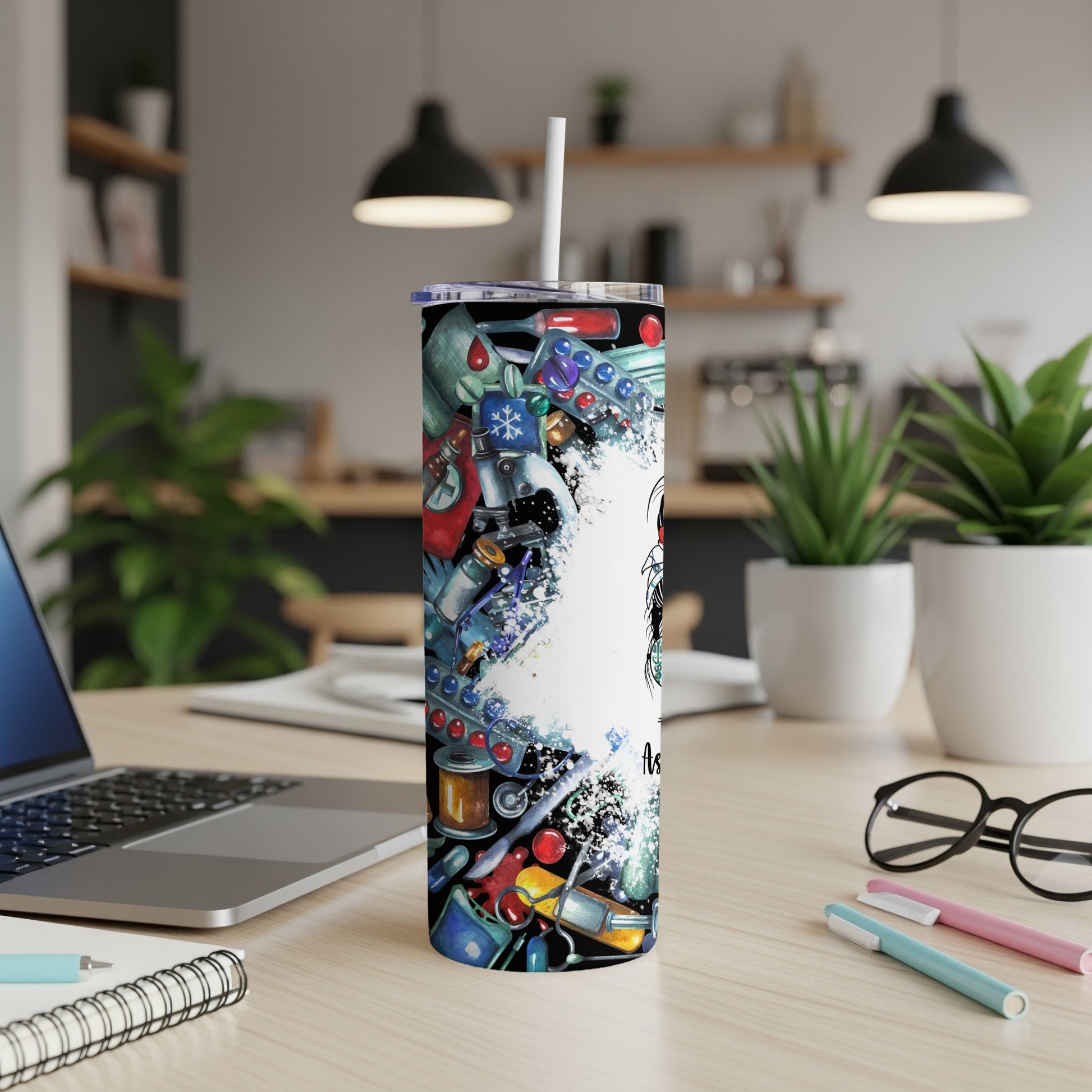 Tall tumbler with medical illustrations and white straw on a desk.