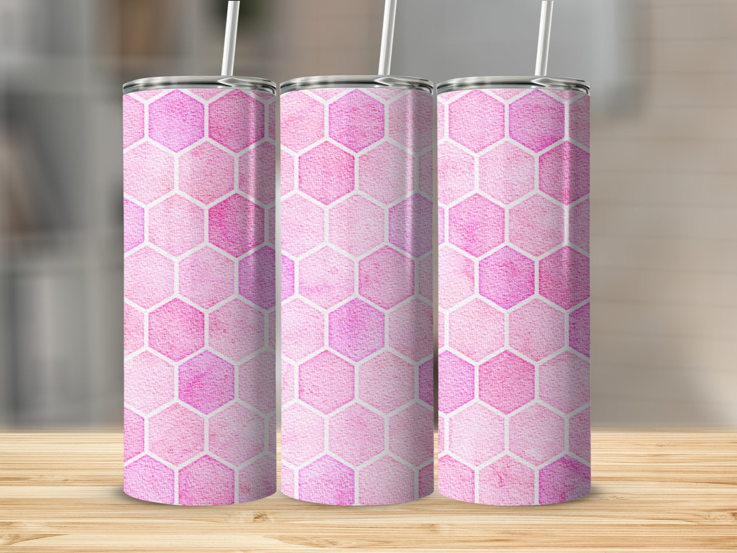 Three pink hexagonal pattern tumblers with straws on a wooden surface.