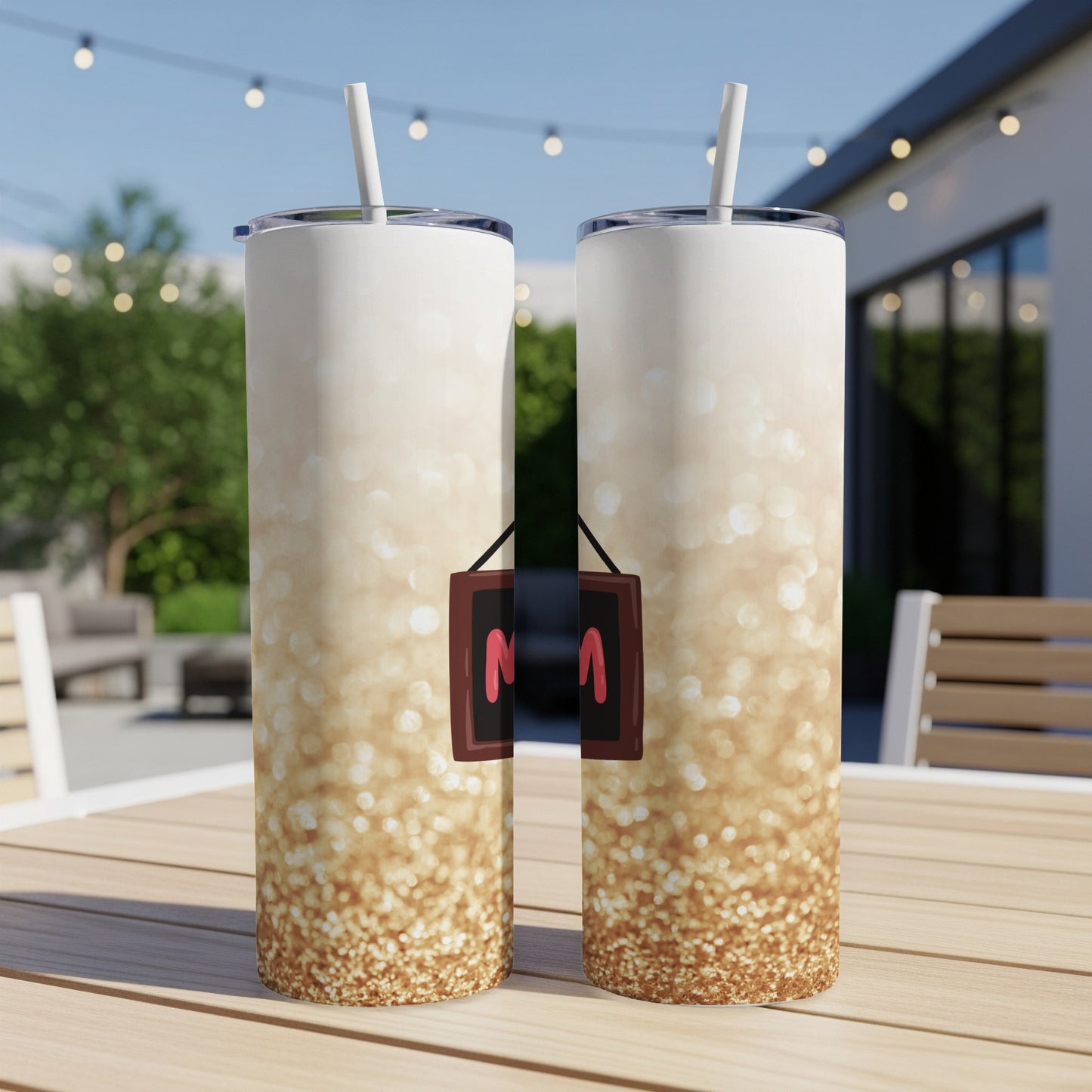 Two glittery tumblers with "Mama" sign on a table outdoors.
