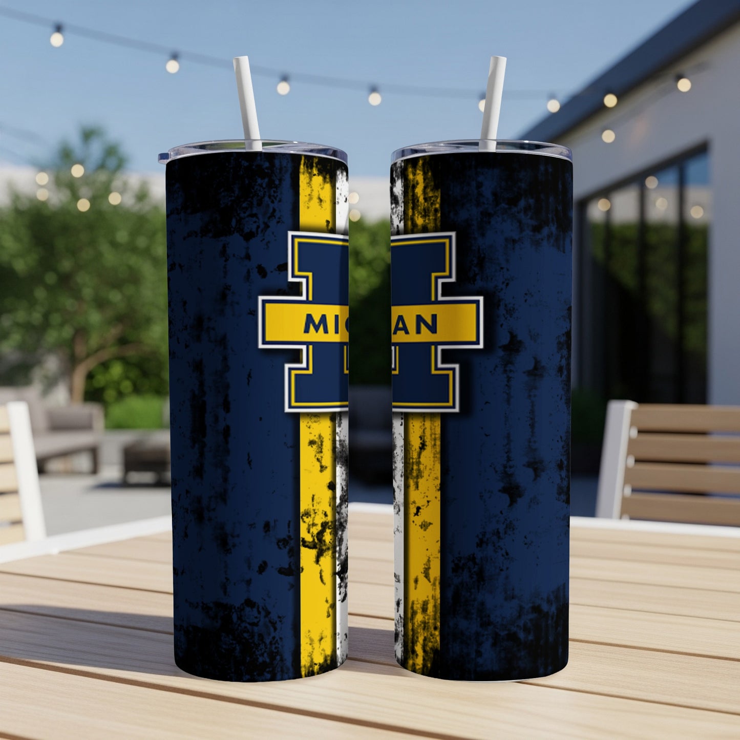 Two Michigan Wolverines tumblers with straws on a wooden table.