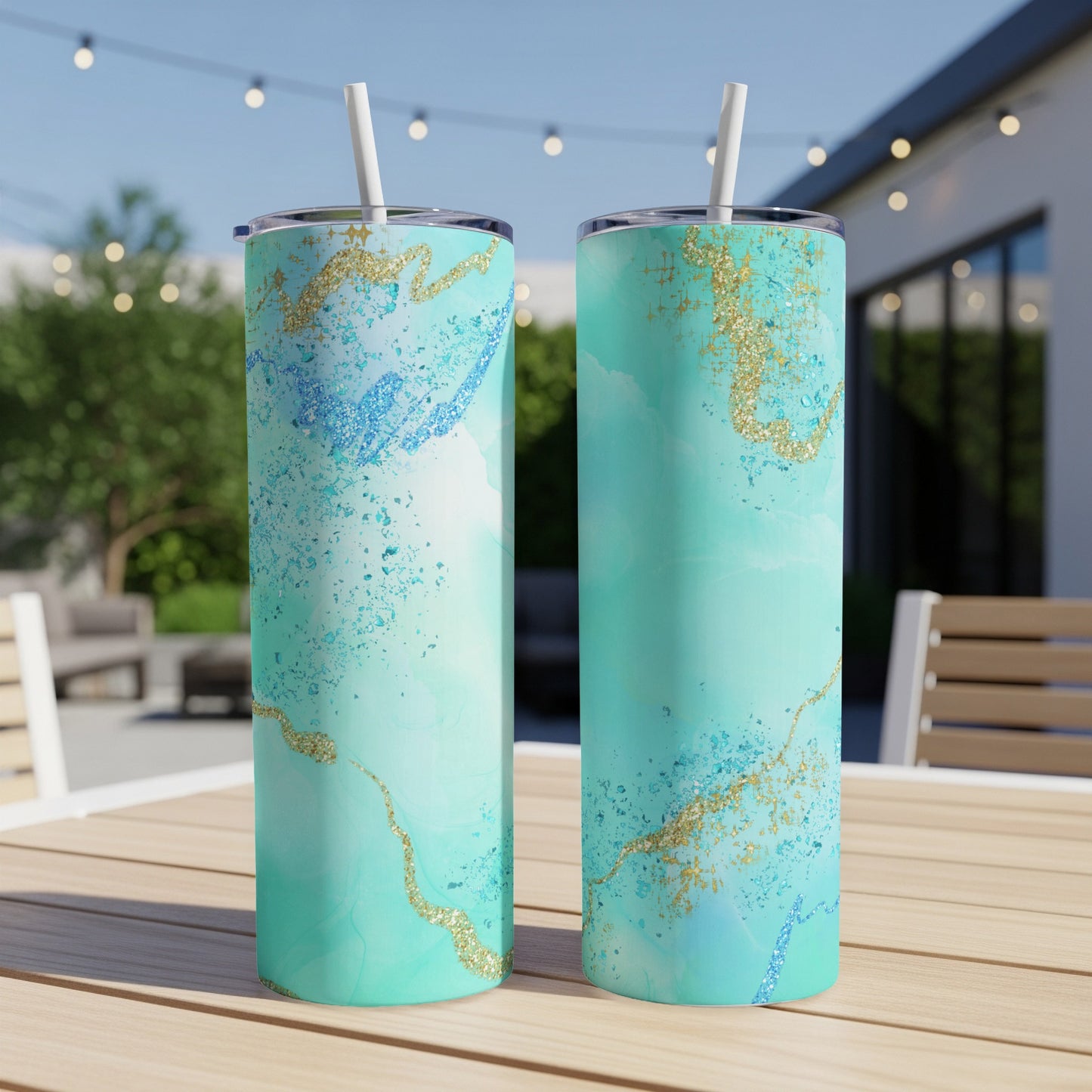 Two teal tumblers with gold and blue marbled accents and straws.