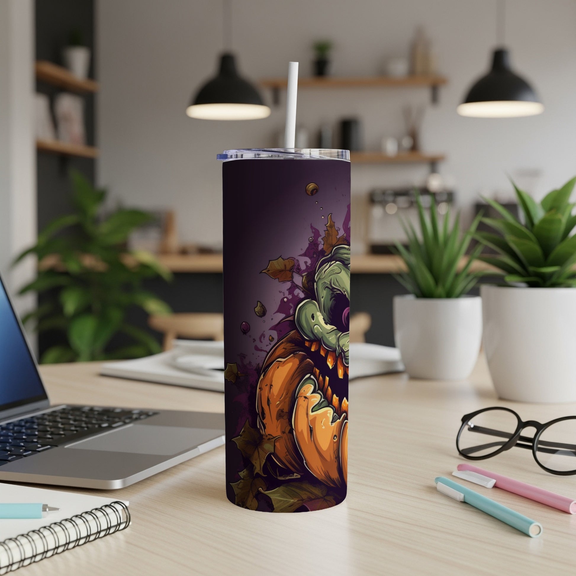 Tall tumbler with a spooky green monster emerging from a jack-o'-lantern and autumn leaves.