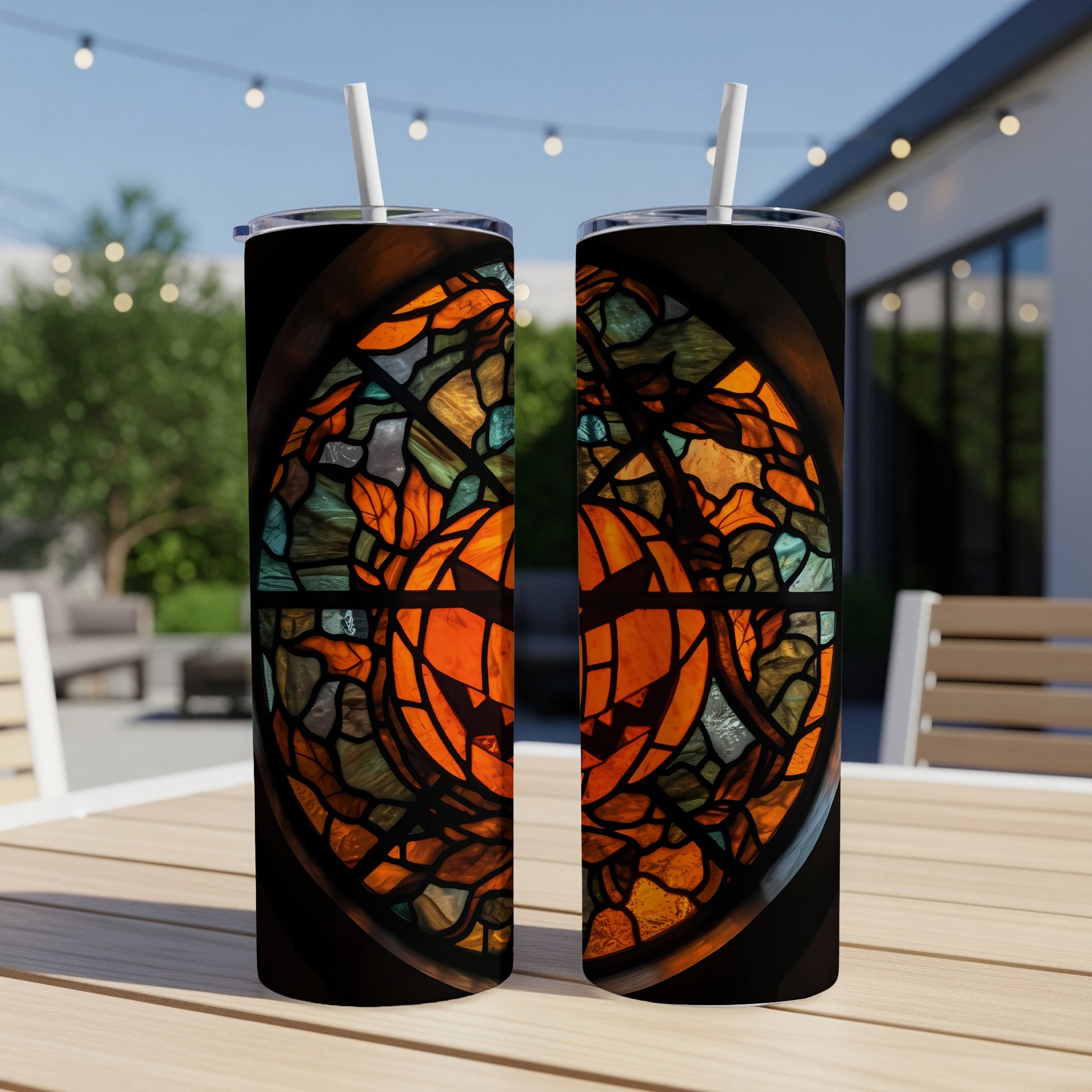 Two tumblers with stained glass pumpkin design on a table.