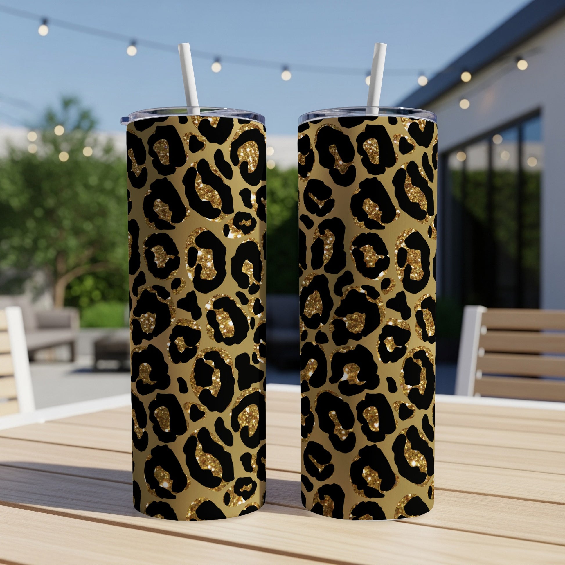 Two stainless steel tumblers with glittery black and gold leopard print and white straws.