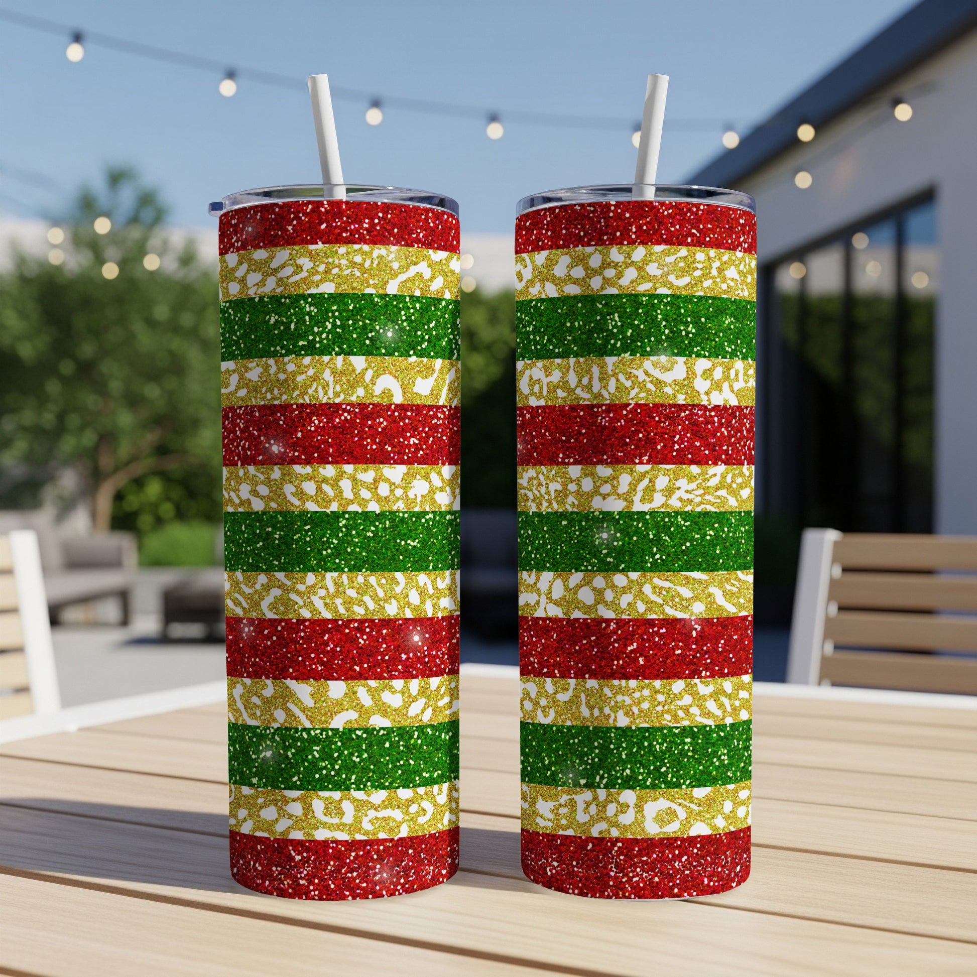 Two glittery tumblers with red, gold, and green stripes sit on a table.