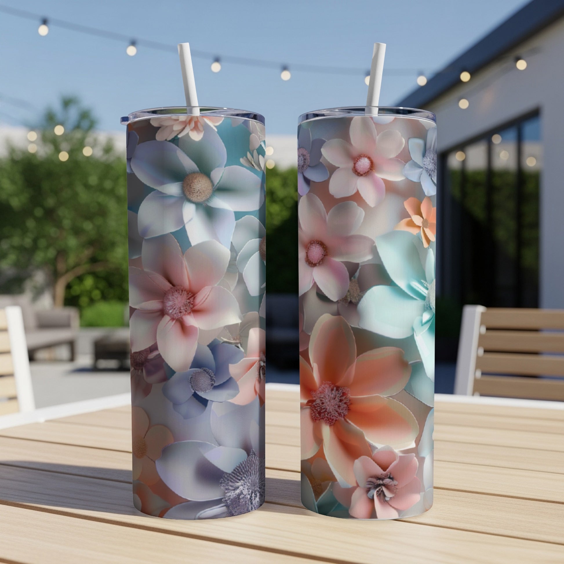 Two tumblers with floral patterns sit on a table outdoors.