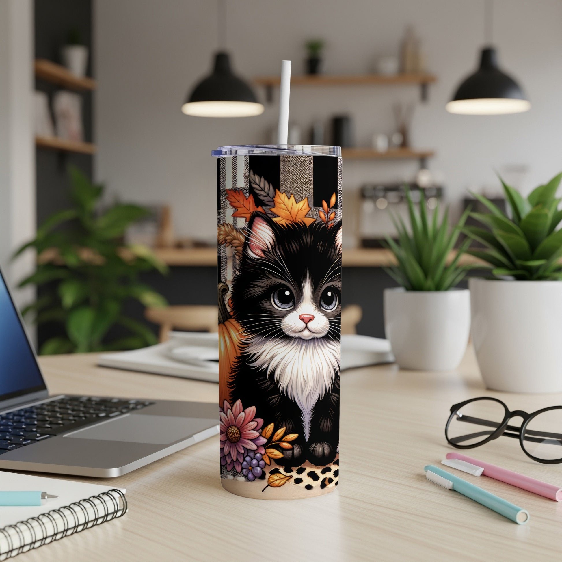 Black and white cat wearing plaid scarf and autumn leaves on tumbler.