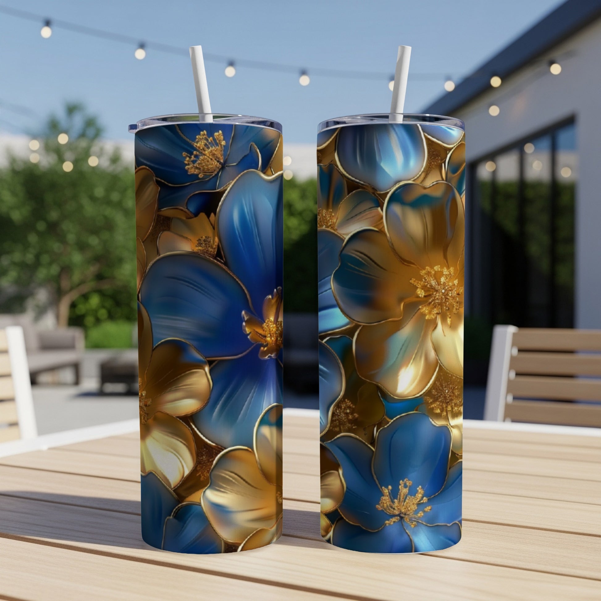 Two blue and gold floral patterned tumblers on a table outdoors.
