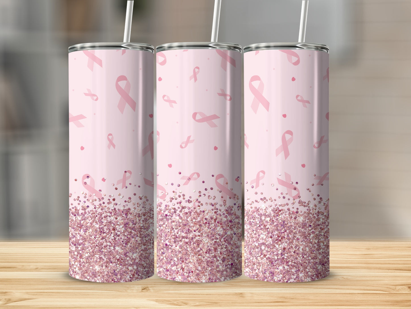 Pink glitter tumbler with scattered pink ribbons on a wooden surface.