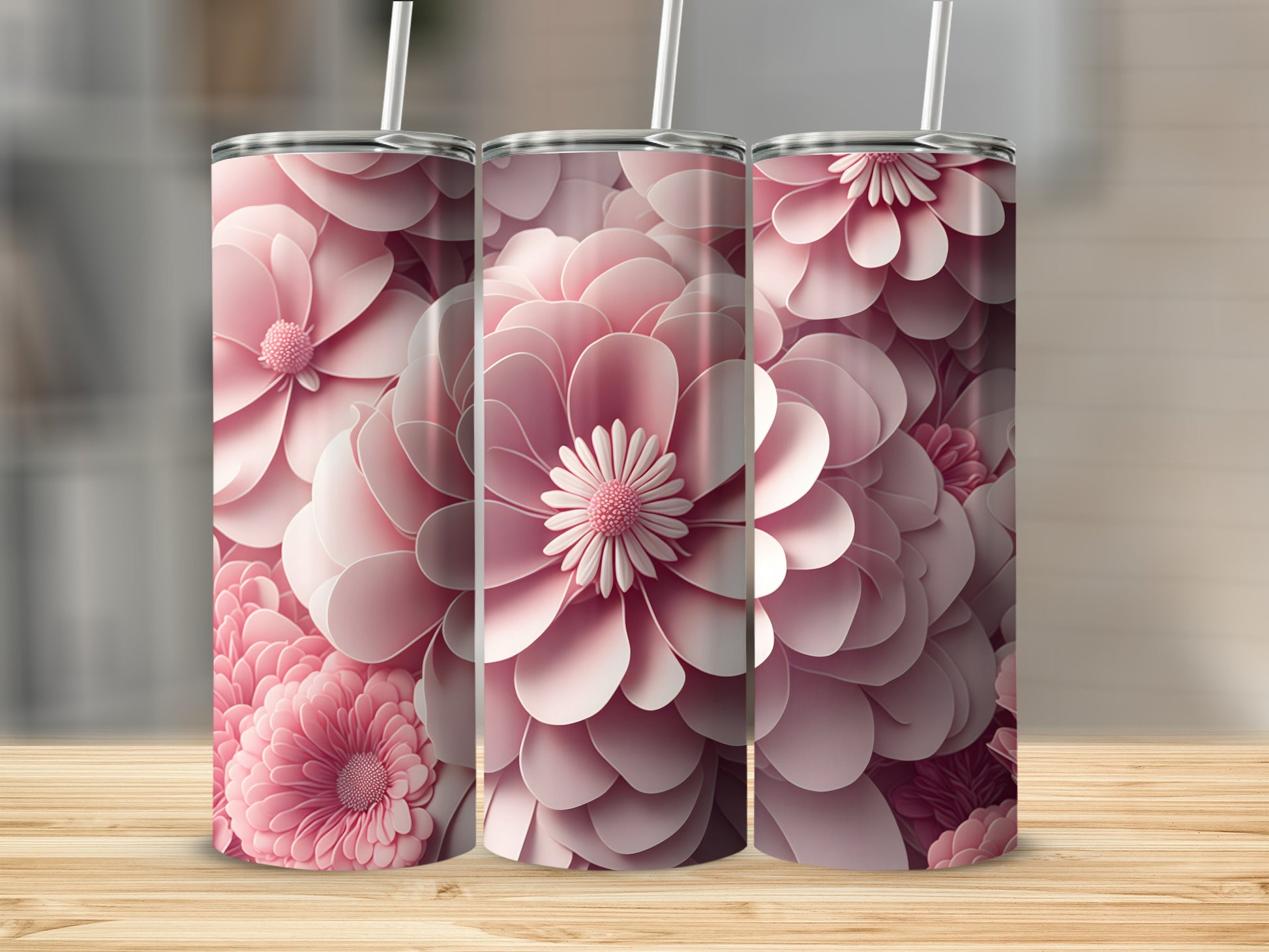 Three pink floral tumblers with straws on a wooden surface.