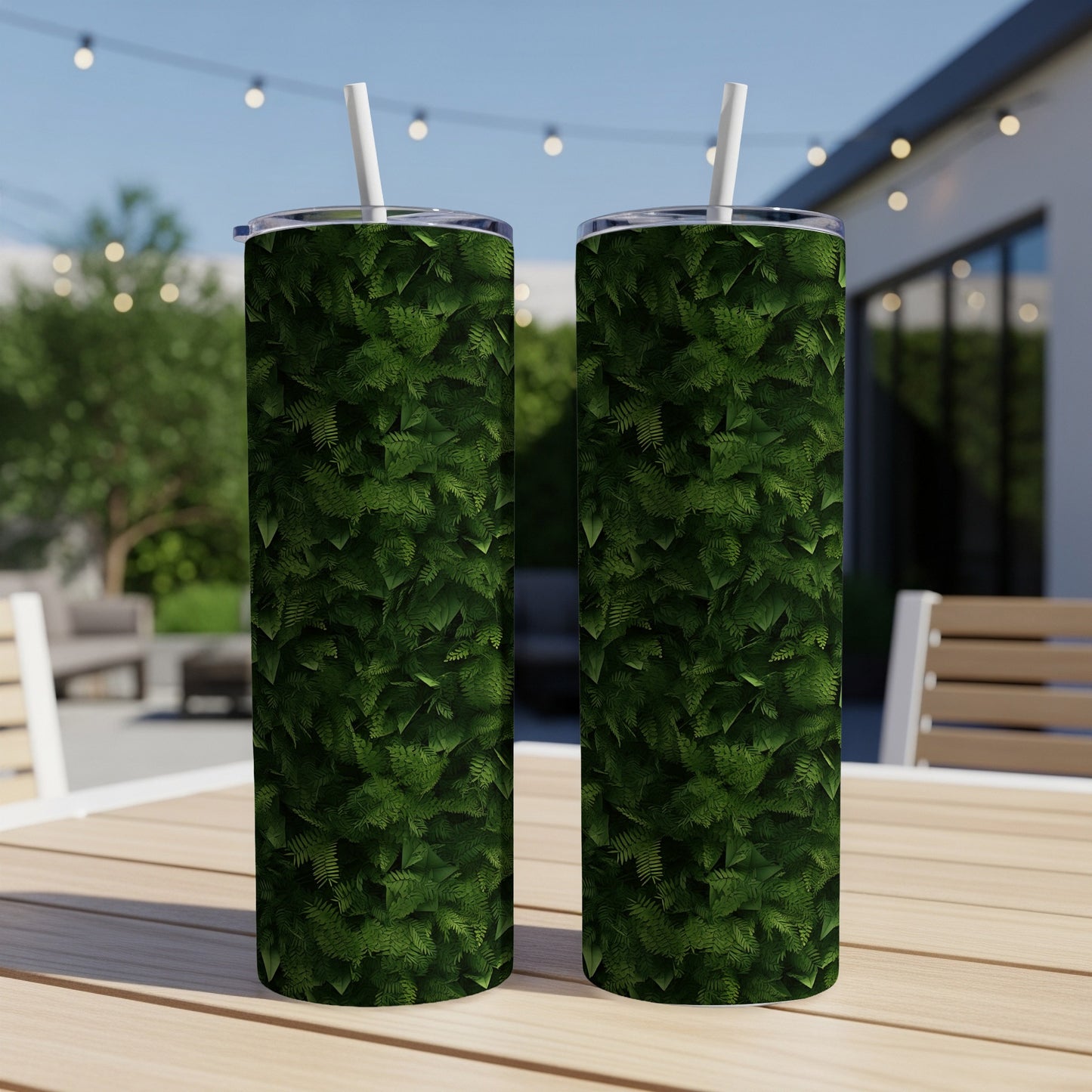 Two tall tumblers with a green fern leaf pattern sit on a table.