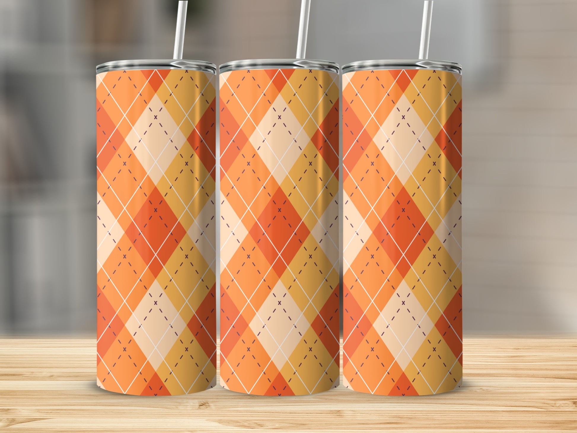Three orange plaid pattern tumblers with straws on a wooden surface.